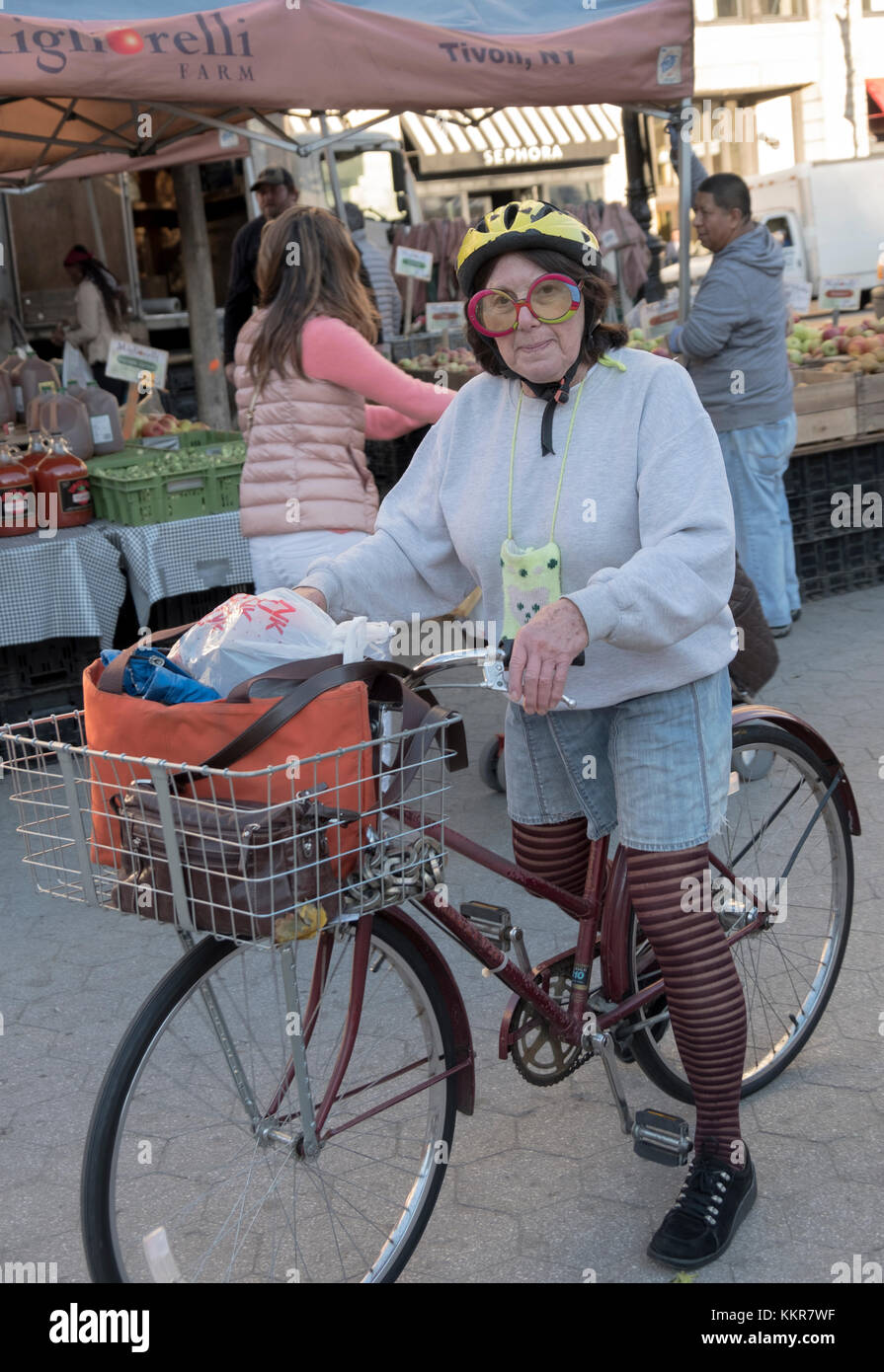A woman on a bicycle with an individual sense of style at the Union Square Green Market in Manhattan, New York City Stock Photo