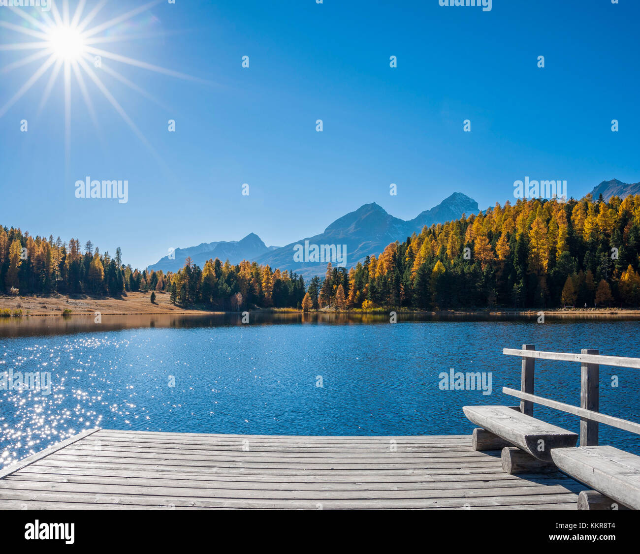 Wooden jetty on mountain lake with bench and sun in autumn, Lake Starz, St. Moritz, Engadin, Grisons, Switzerland Stock Photo