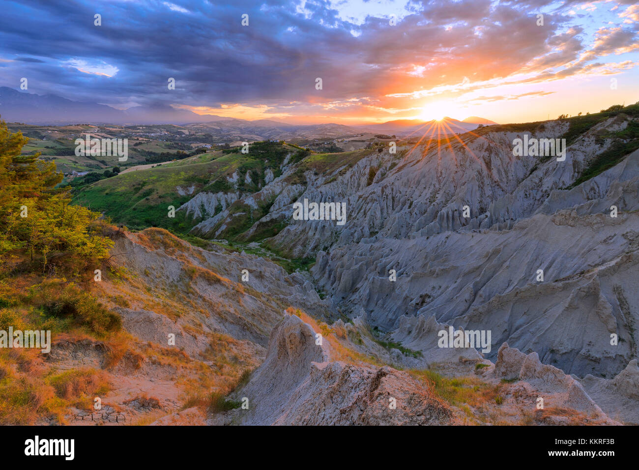 Sun filters through the clouds during sunset illuminating the Calanchi of Atri, Abruzzo, Italy. Stock Photo