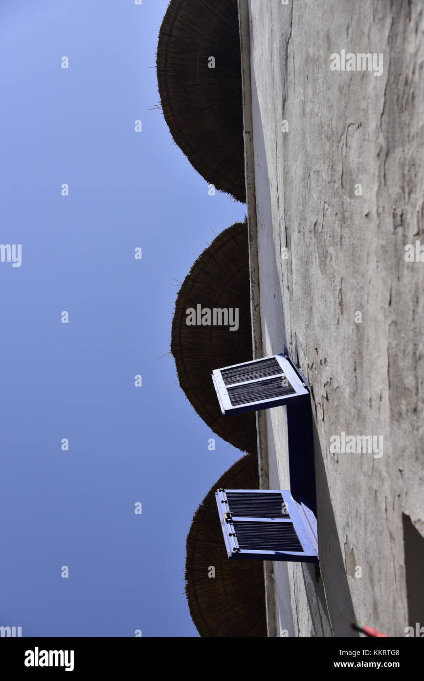 Upward view of white plaster wall, showing open shutter and overhung by ...
