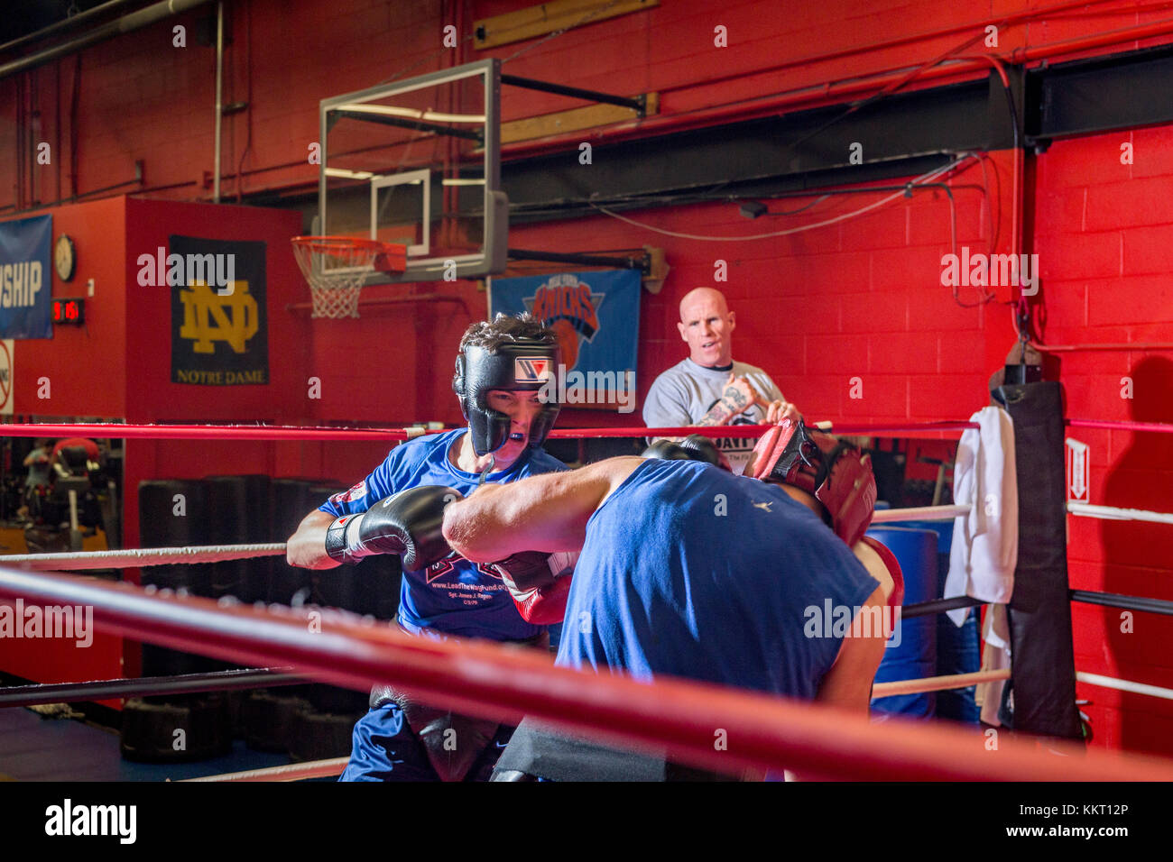Amateur boxers wearing protective headgear sparring in a gym while
