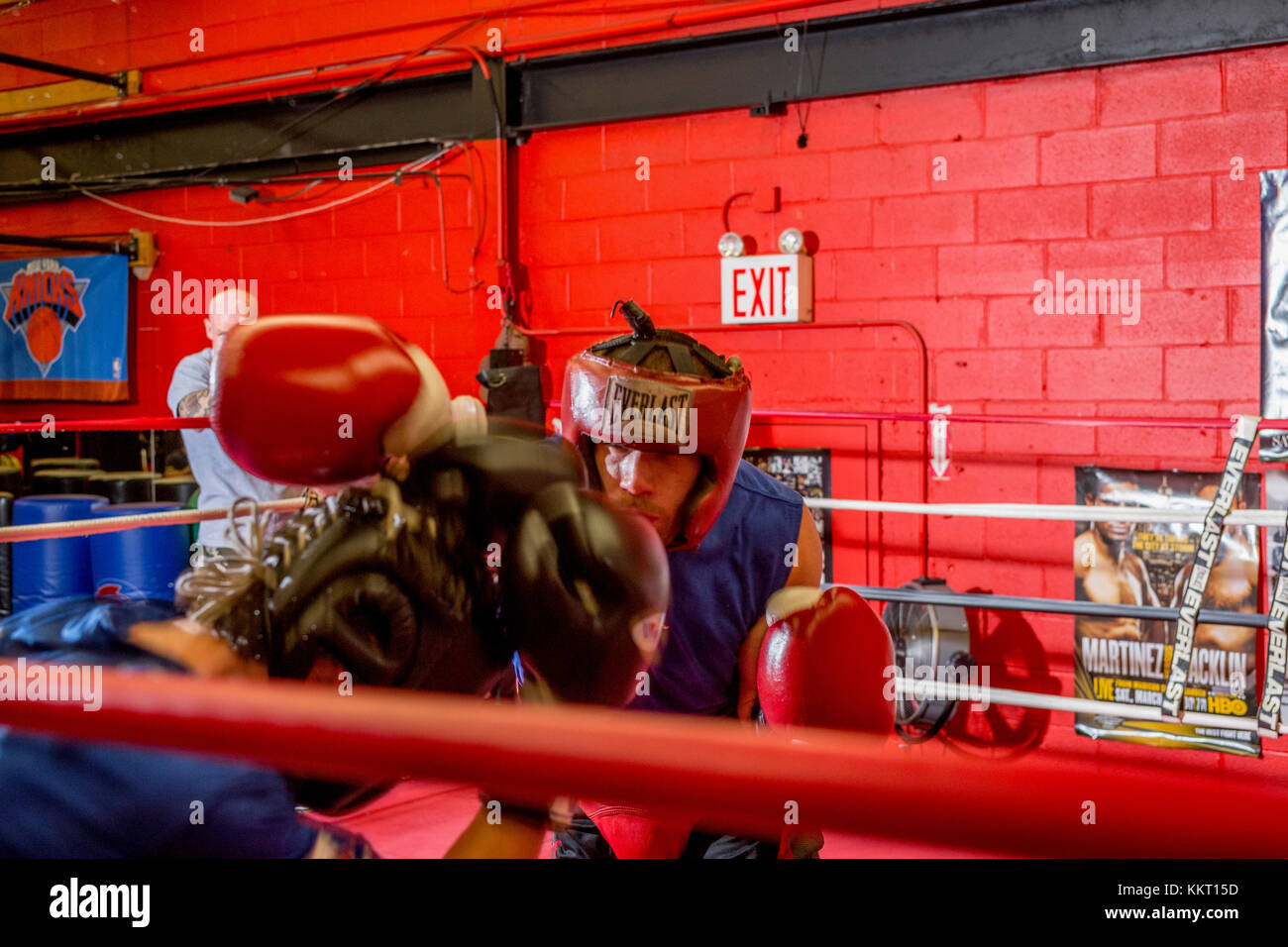 Amateur boxers wearing protective headgear sparring in a gym while