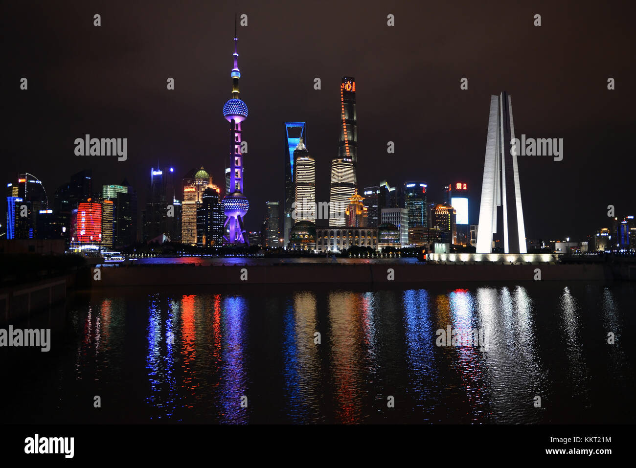 Shanghai, China - November 18, 2017:  Night shot of The Monument to the People's Heroes, left foreground, taken from The Bund with the Pudong skyline  Stock Photo