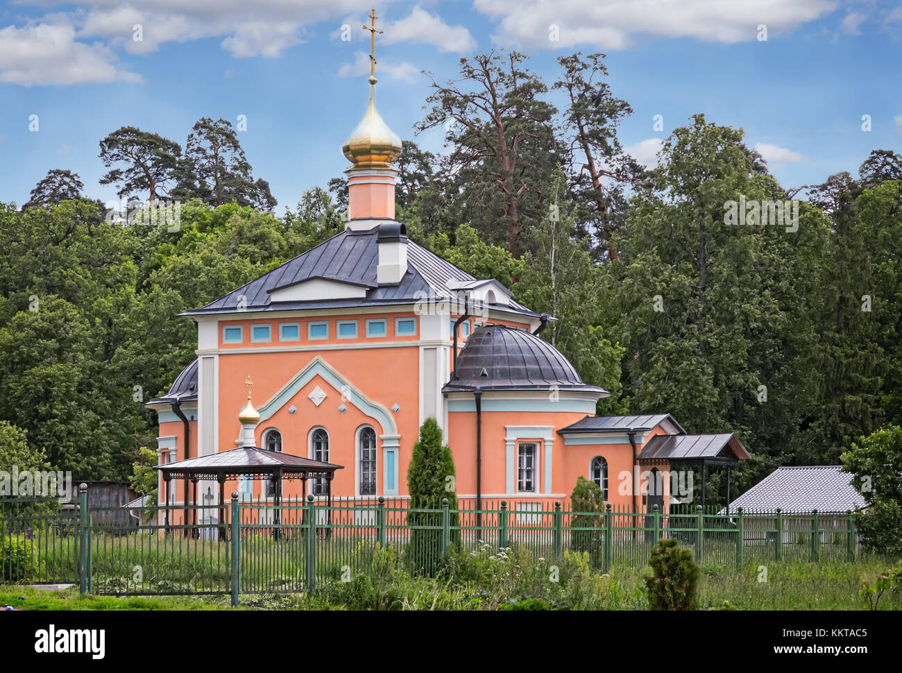 A beautiful Orthodox temple located on a hill surrounded by flowers and plants: arborvitae, blue spruce, shrubs. Stock Photo