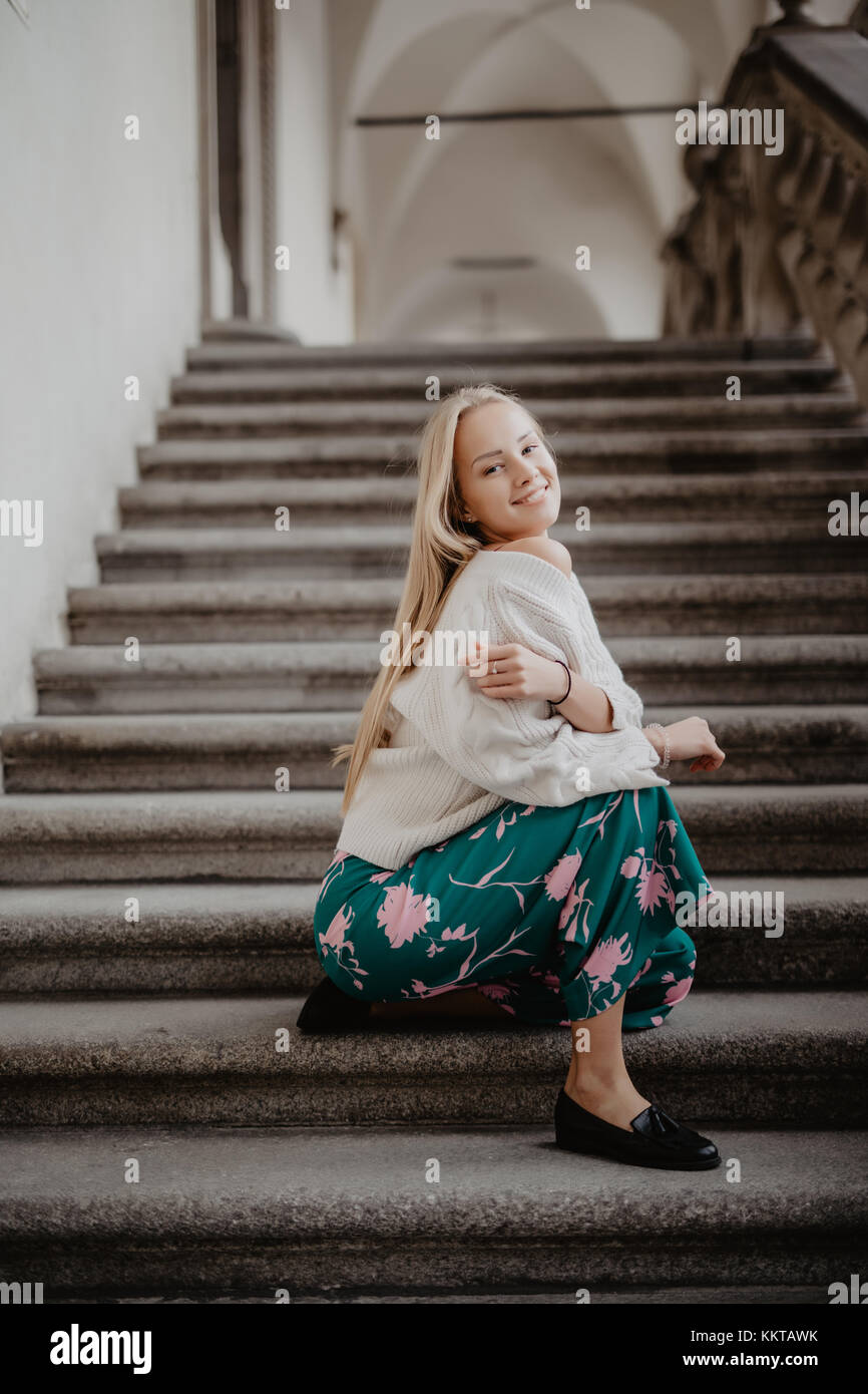 Stylish blonde young woman sitting on the stairs Stock Photo - Alamy
