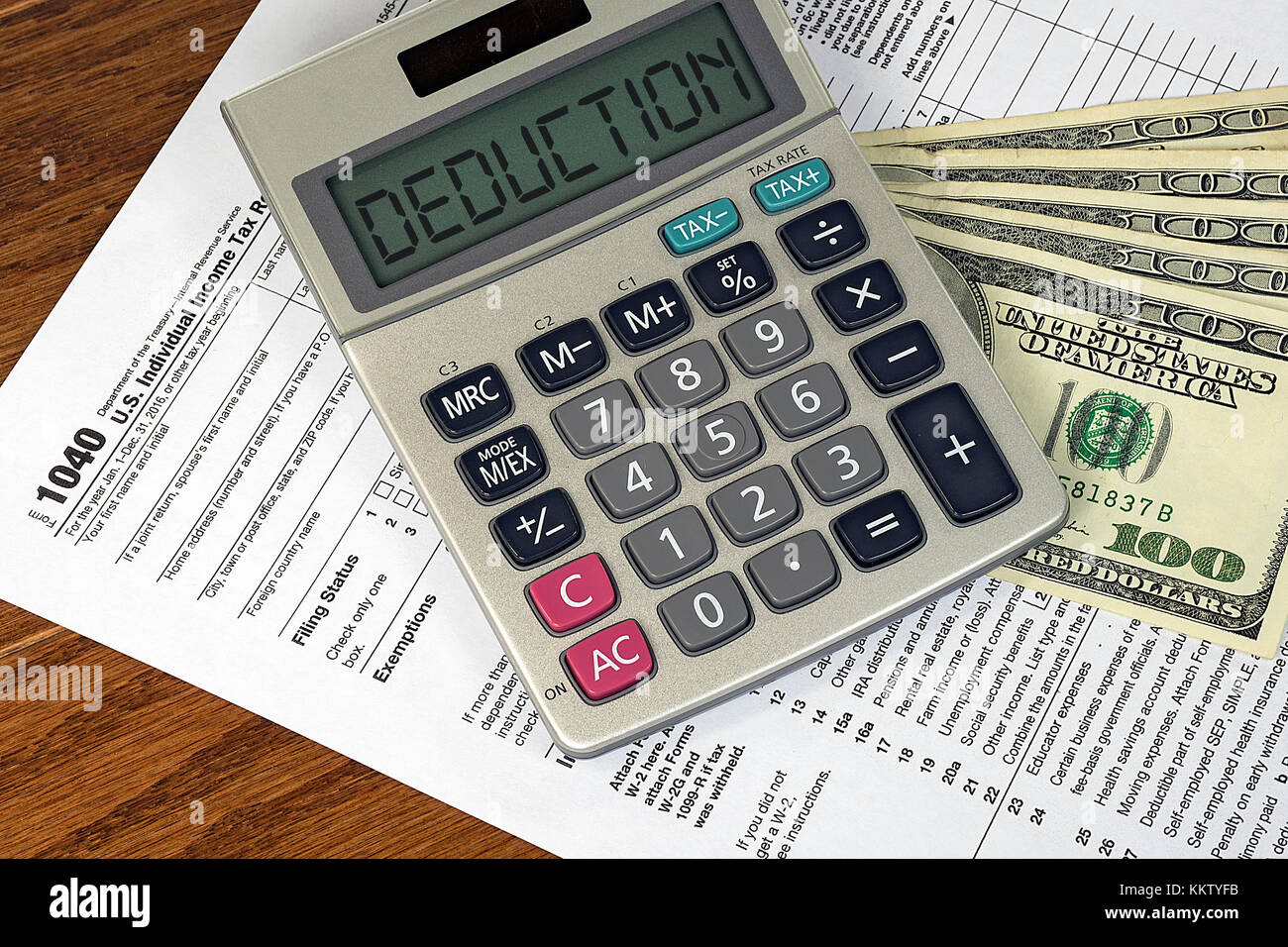 deduction text on silver calculator with American hundred dollar bills on 1040 income tax form Stock Photo