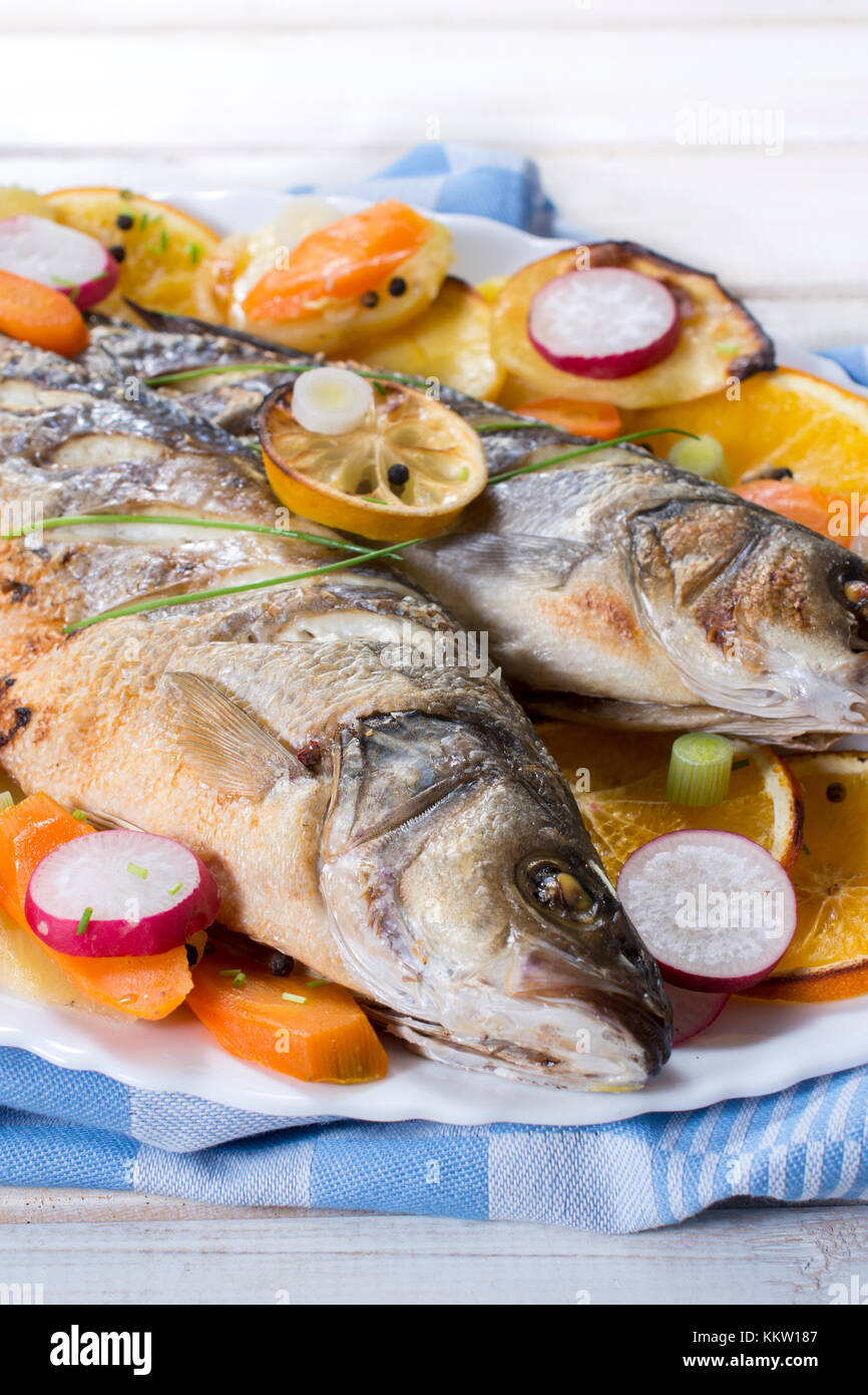 Prepared Bass fish with vegetables and fruit in the plate Stock Photo