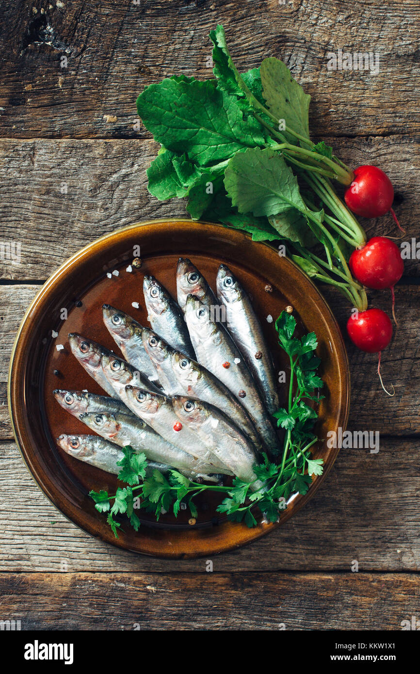 Smelt fishes in the plate on wooden background from above Stock Photo