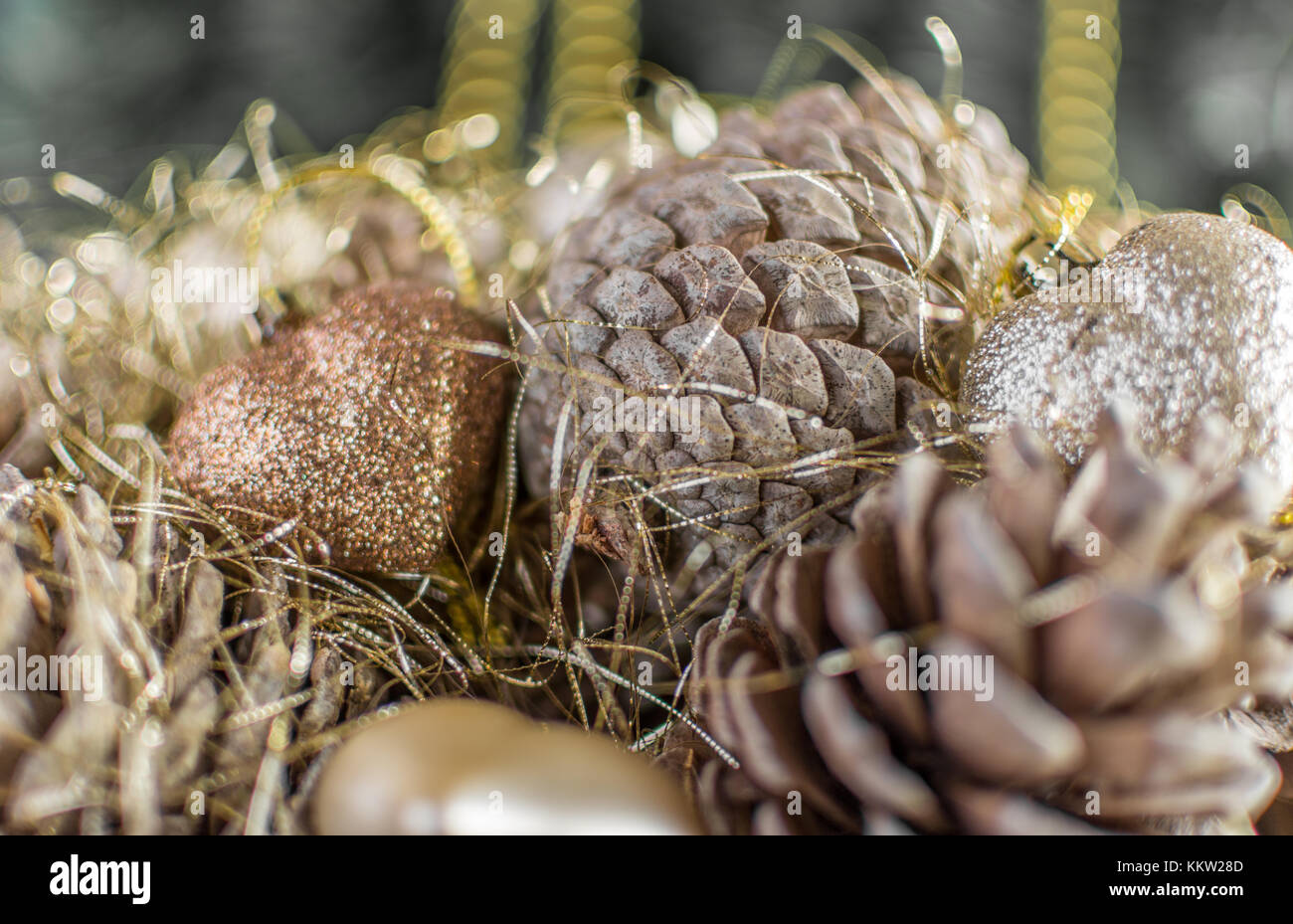 Colorful golden Christmas decorations of a wooden basket with pine cones made with desaturated grainy effect. Extreme shallow depth of field and color Stock Photo