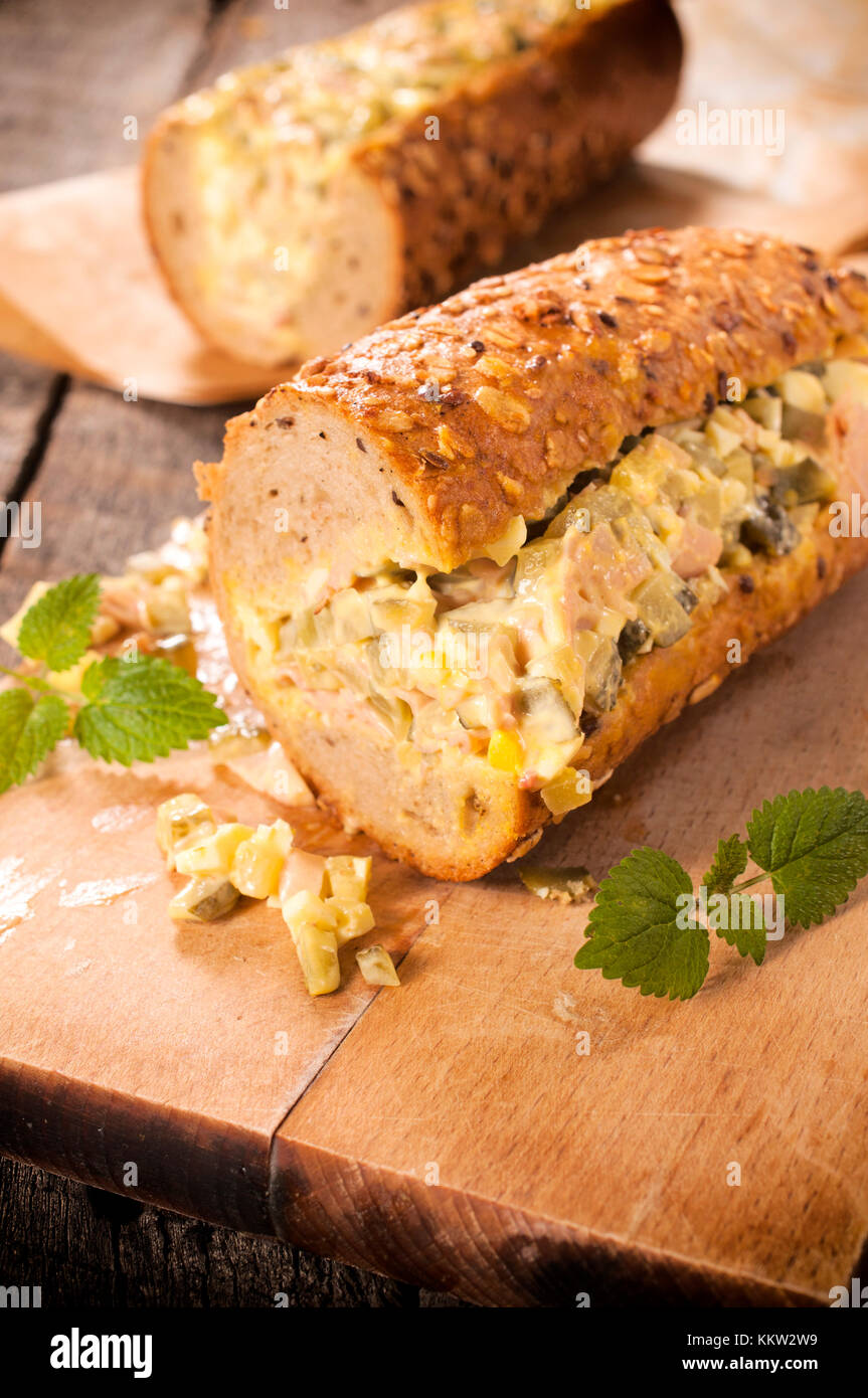 Sub sandwich stuffed with gourment salad on the wooden board Stock Photo