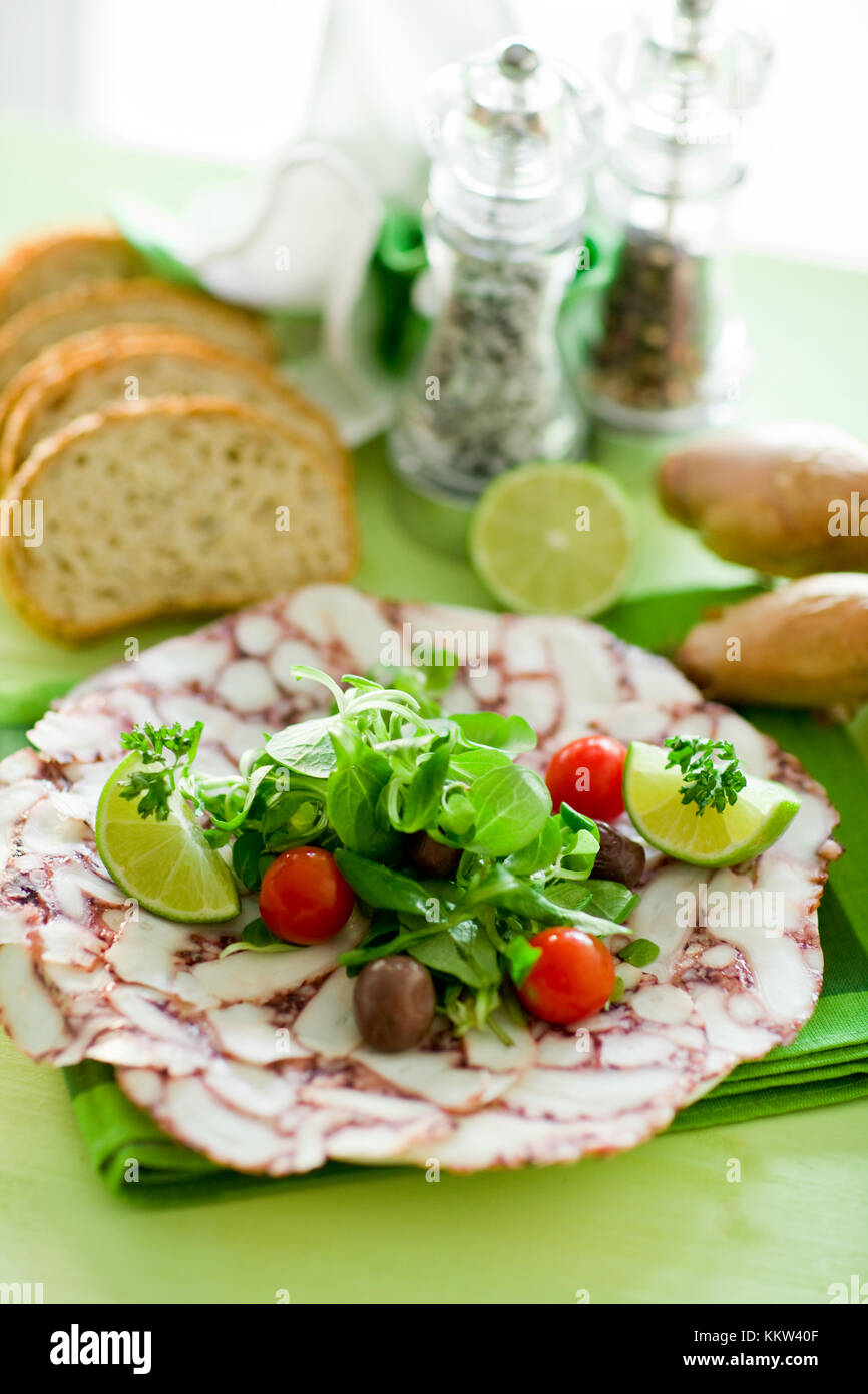 photo of delicious octopus carpaccio with mixed salad illuminated by daylight Stock Photo