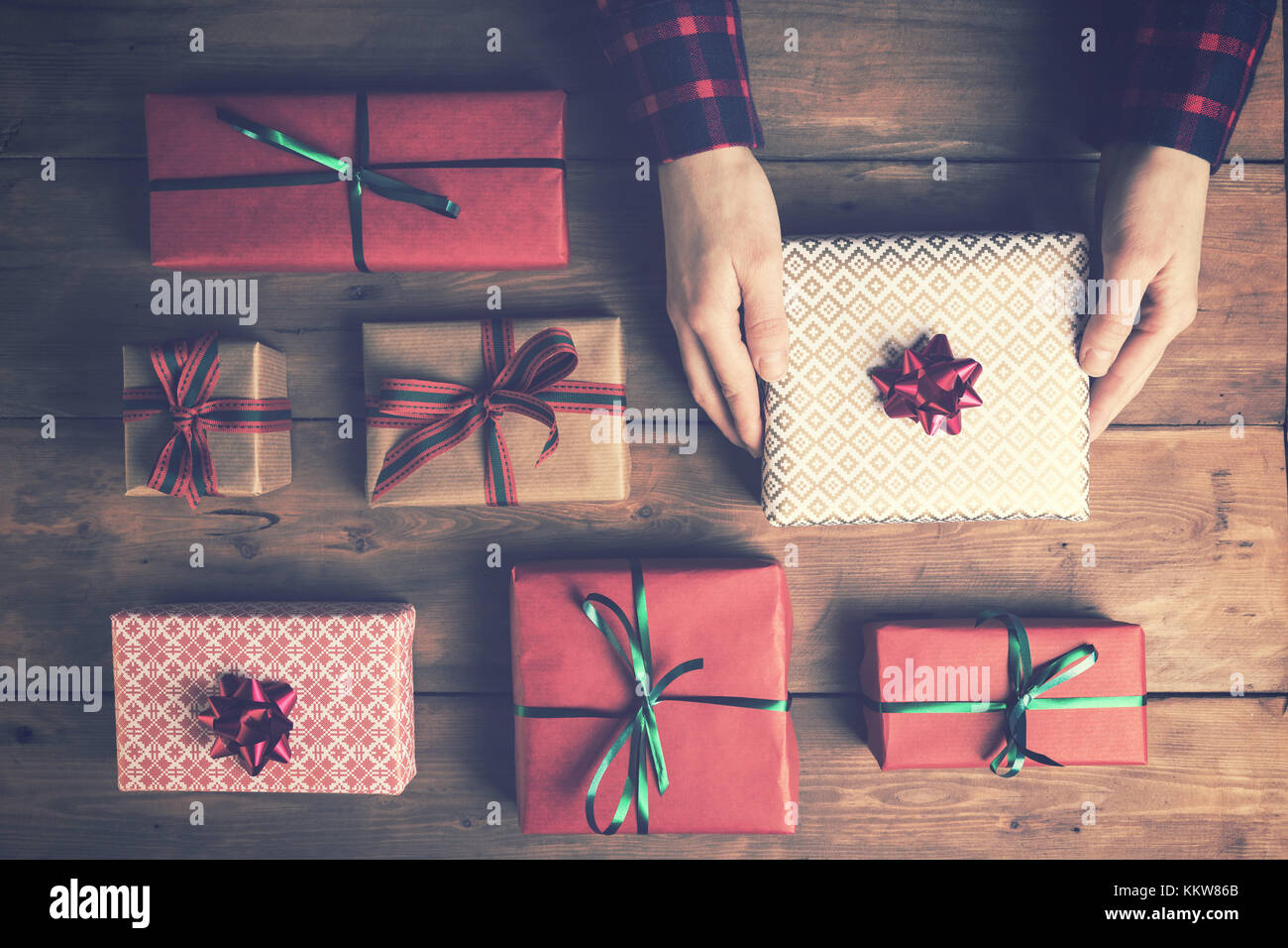 woman's hands holding packed gift box on old wooden table. top view Stock Photo