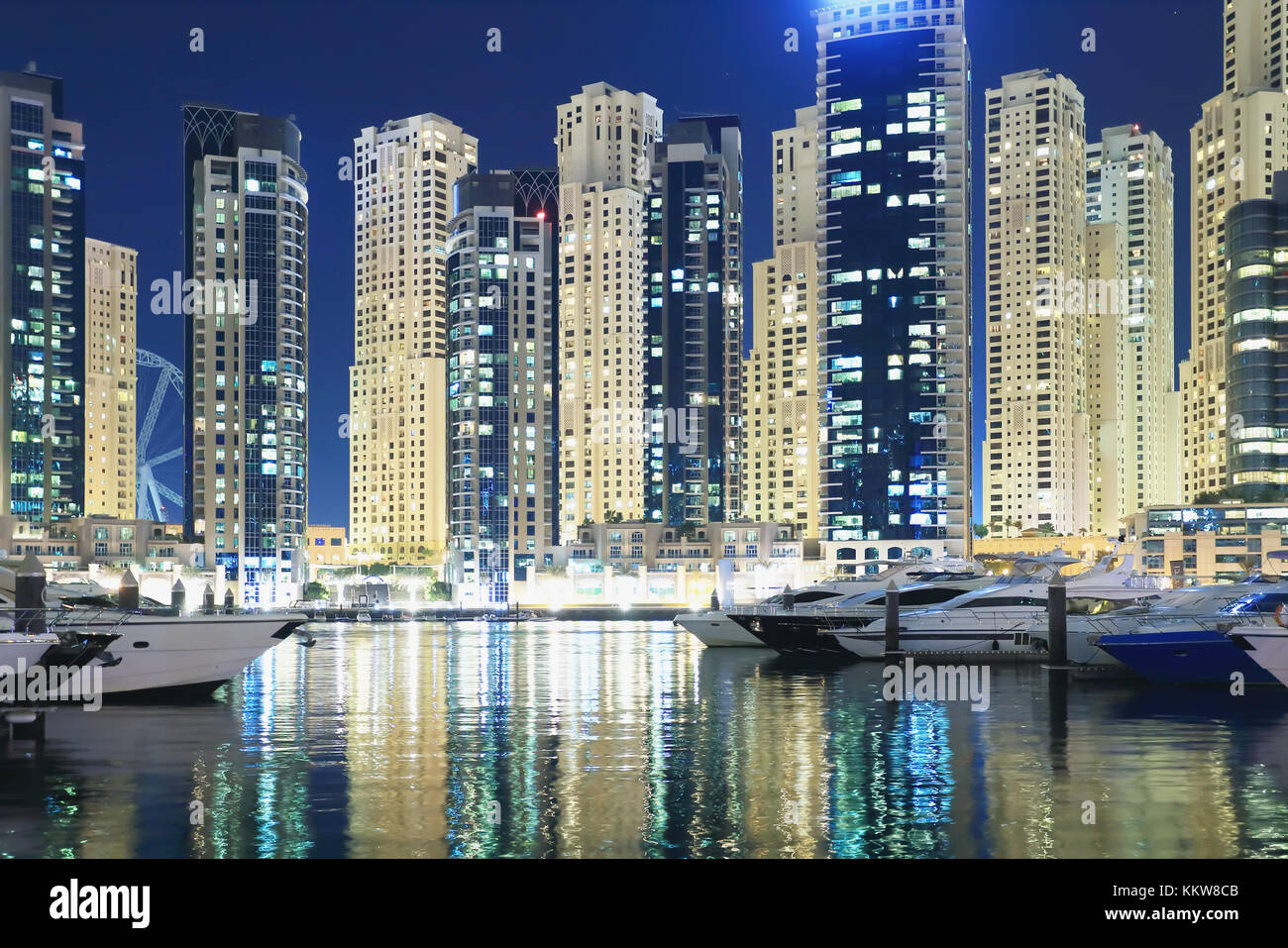 Luxury Dubai district with yachts and skyscrapers at night. Beautiful illumination of night Dubai cityscape. Stock Photo