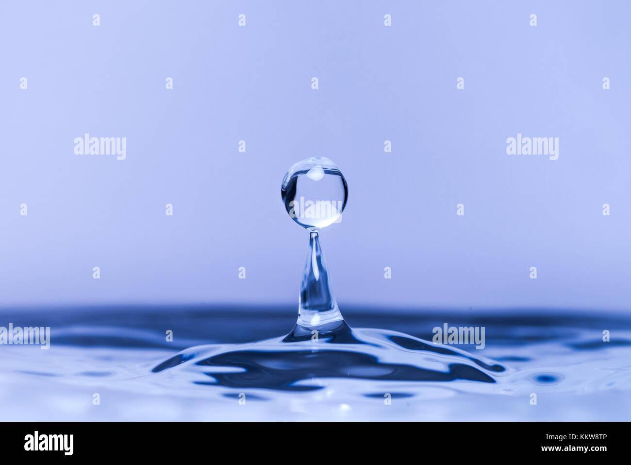 Close up of water drop dropping into water Stock Photo - Alamy