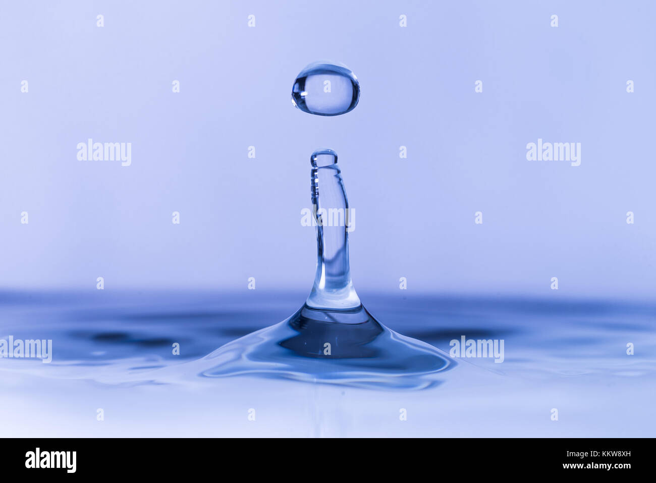 Close up of water drop dropping into water Stock Photo