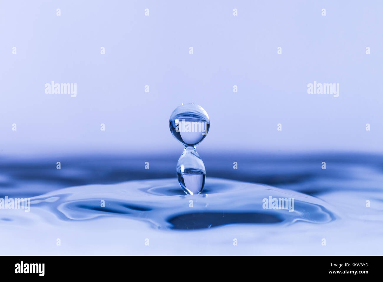 Close up of water drop dropping into water Stock Photo - Alamy