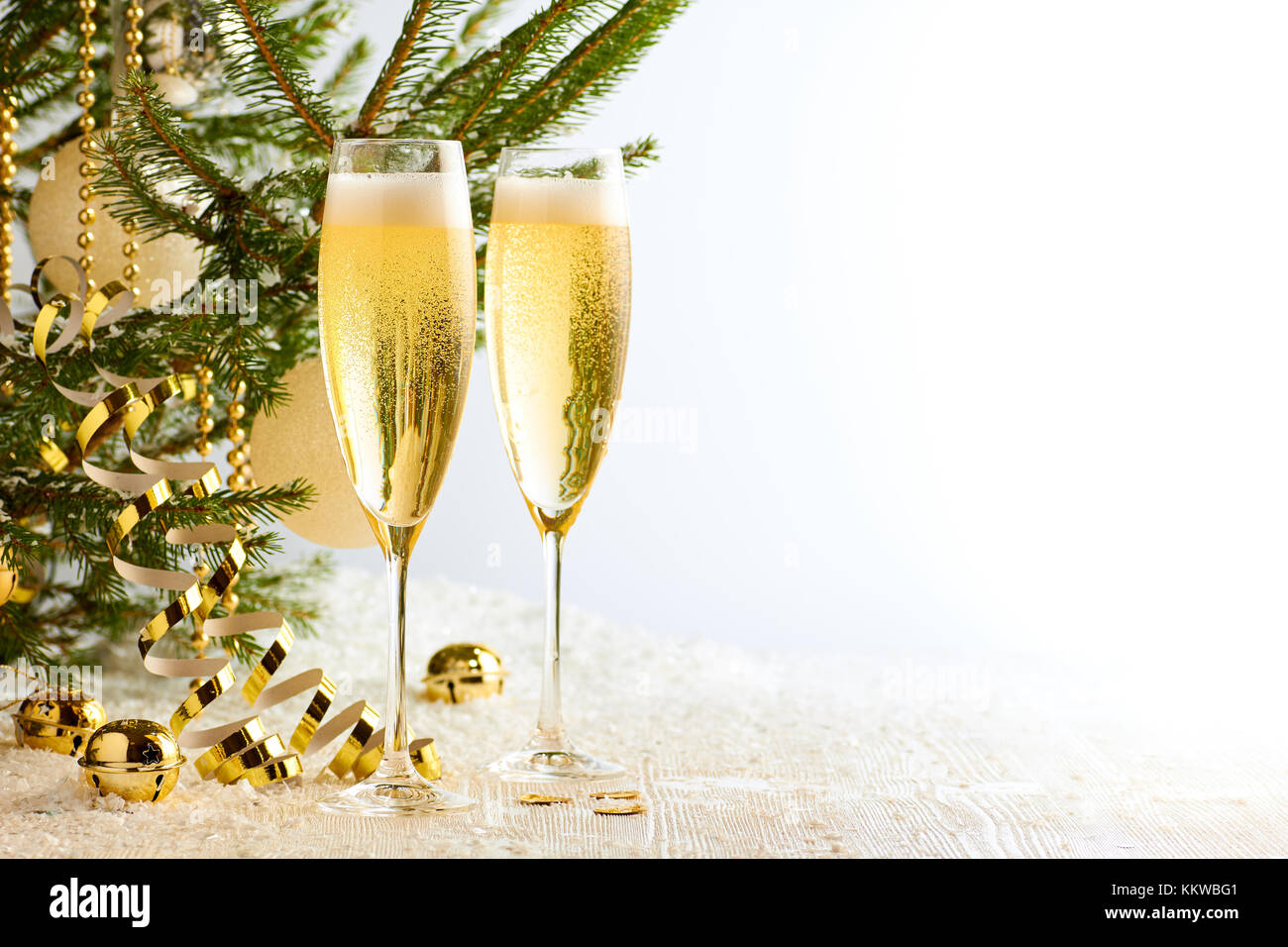 Two glasses of champagne ready to bring New Year on Christmas tree background Stock Photo