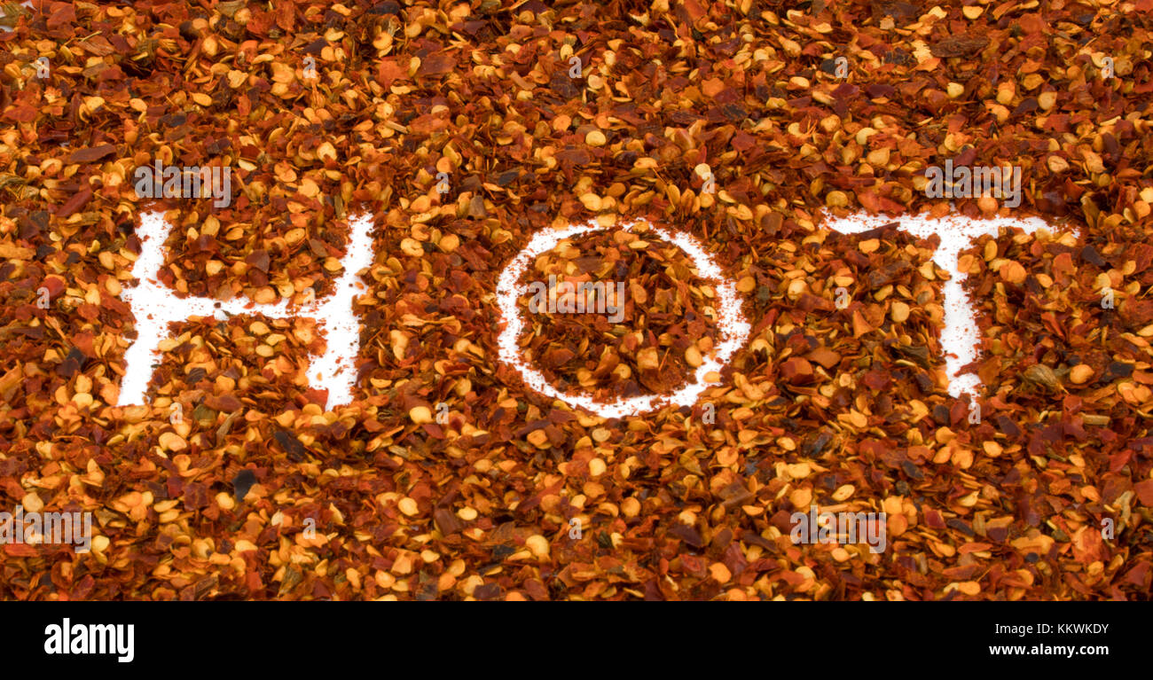 Word Hot write in dried chili pieces red pepper crushes macro background - hot concept Stock Photo