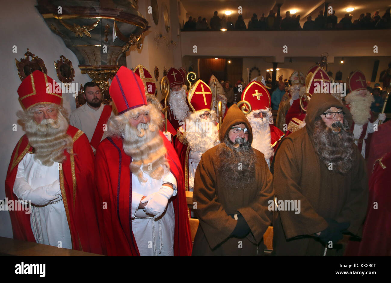 Santa Claus and Knecht Ruprecht impersonators stand in the parish church Saint Martin for the service in Missen, Germany, 01 December 2017. Over 30 Santa Clauses from various countries met in the Allgaeu region. Photo: Karl-Josef Hildenbrand/dpa Stock Photo