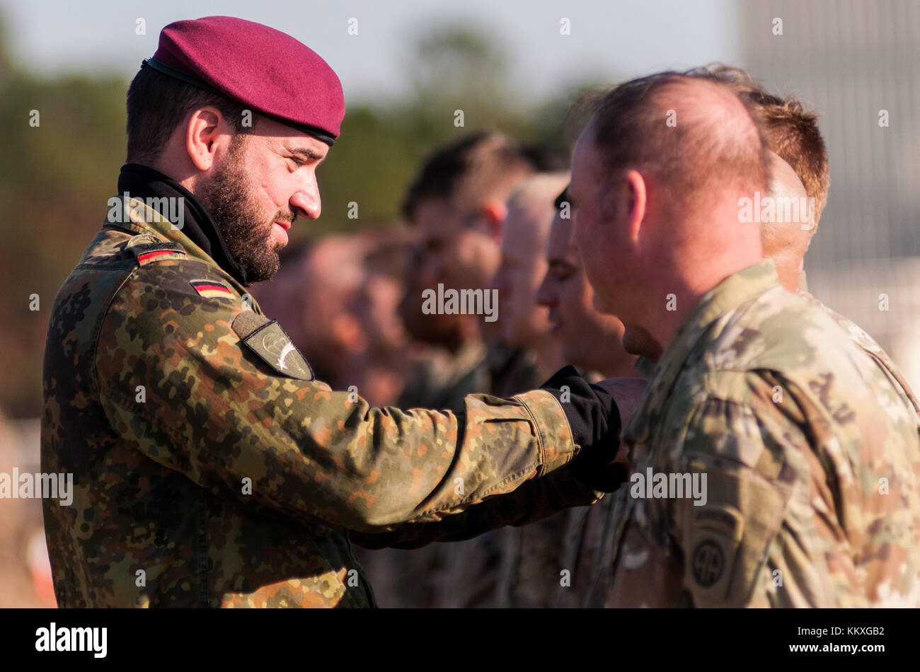 Fort Bragg, NC, USA. 1st Dec, 2017. Dec. 1, 2017 - FORT BRAGG, N.C., USA - German Army Lt. Col. Tomas Tintor, presents his nation's jump wings to U.S. Army paratroopers after successfully completing a jump onto Sicily Drop Zone, Friday, at the 20th Annual Randy Oler Memorial Operation Toy Drop. The airborne operation, hosted by the U.S. Army Civil Affairs & Psychological Operations Command (Airborne), is the world's largest combined airborne operation with paratroopers from nine allied nations participating. The annual event allows paratroopers the opportunity to help children i Stock Photo