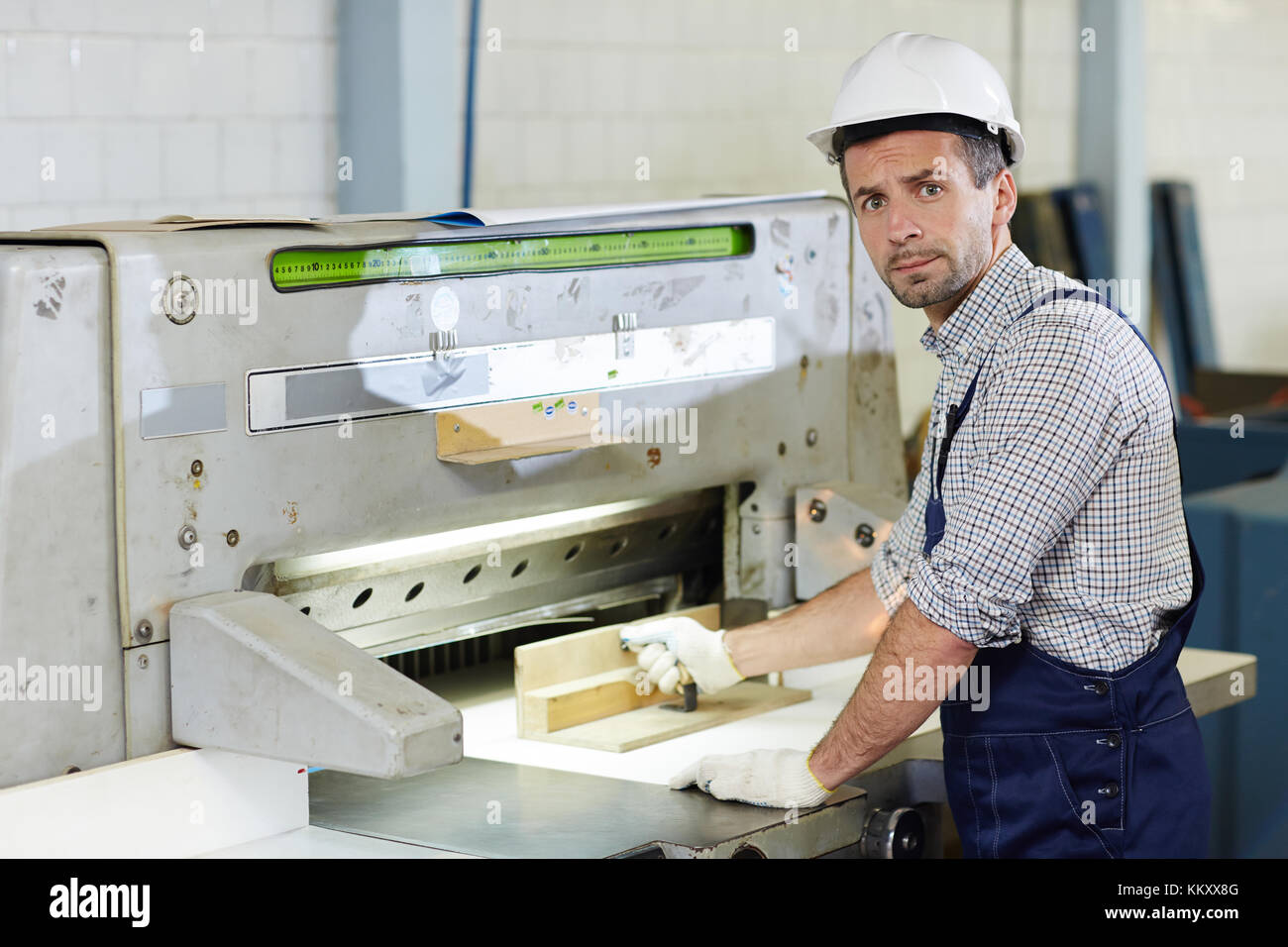 Mid-aged worker in uniform producing technical details on industrial machine Stock Photo