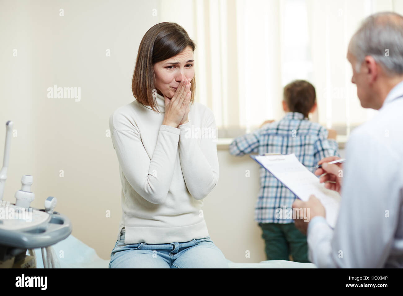 Young woman crying while listening to doctor advice and precriptions after examine Stock Photo
