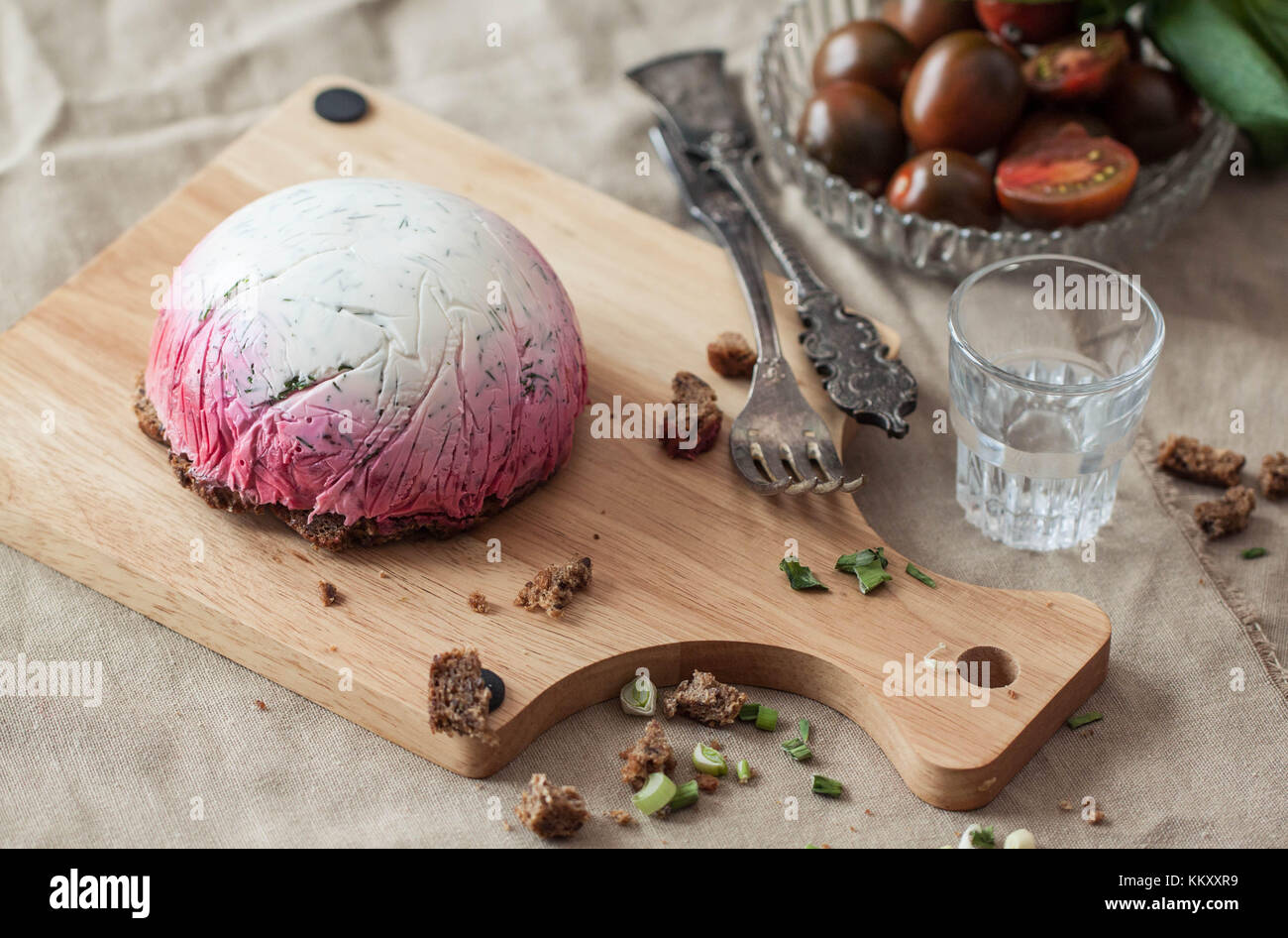 Delicious snack salad herring under a fur coat on wooden board with fork and russian vodka Stock Photo