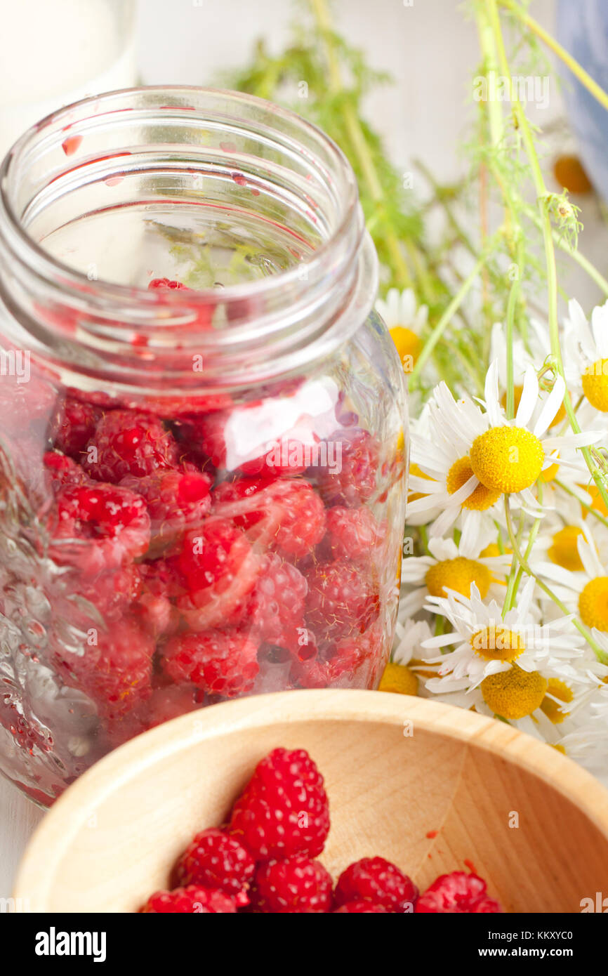 Fruity Pots Raspberry Glass pot of fresh ripe raspberries with camomile flowers on white ...