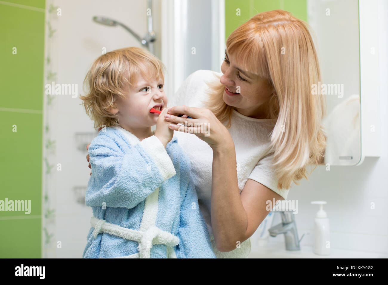 Mother teaching and helping kid son how to brush his teeth Stock Photo