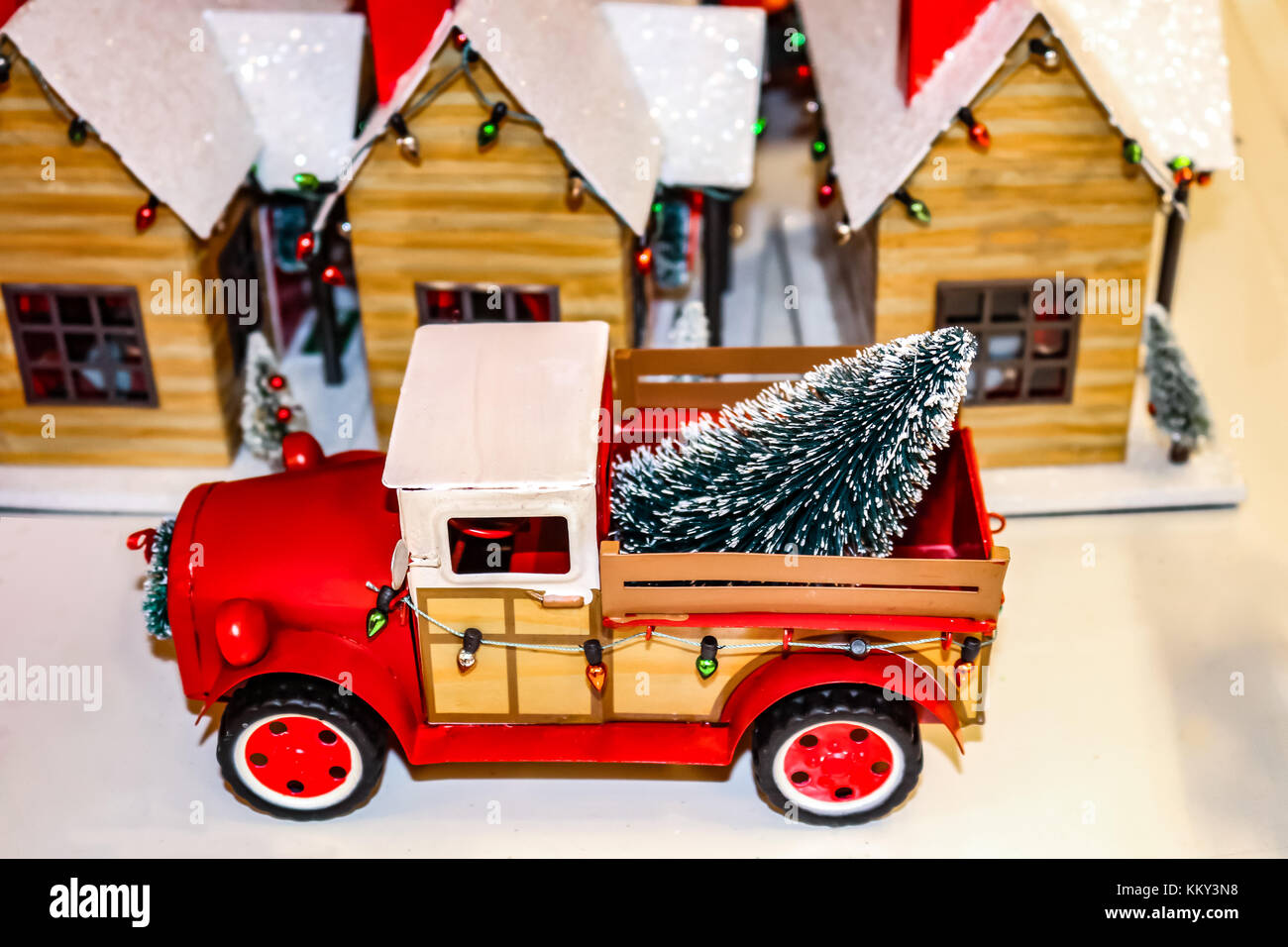 Vintage red toy pickup truck with Christmas lights and tree in back.jpg in front of a toy country Christmas village Stock Photo