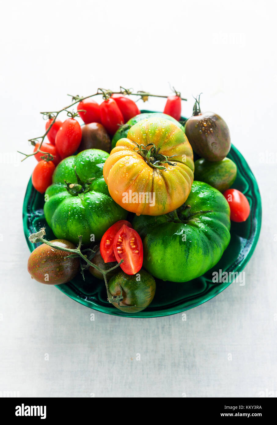 different kinds, types and color of tomatoes on a white stone table ...