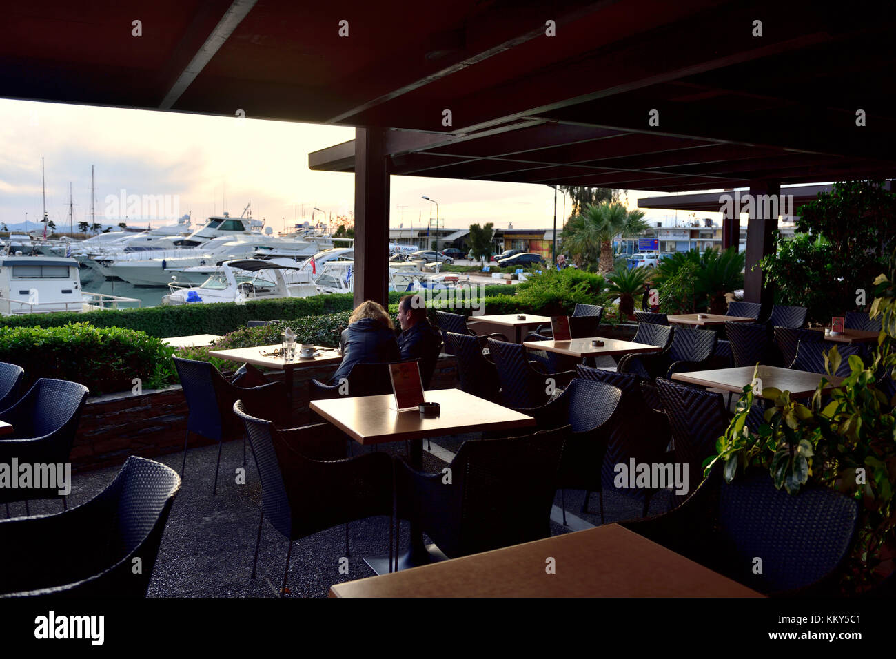 Restaurant overlooking seaside and harbour in Athens suburb of Glyfada near sunset, Saronic Golf, Greece Stock Photo