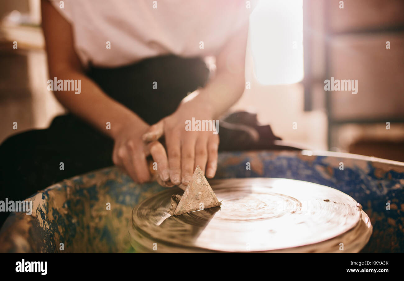 Woman potter cleaning the potters wheel using a triangular scraping