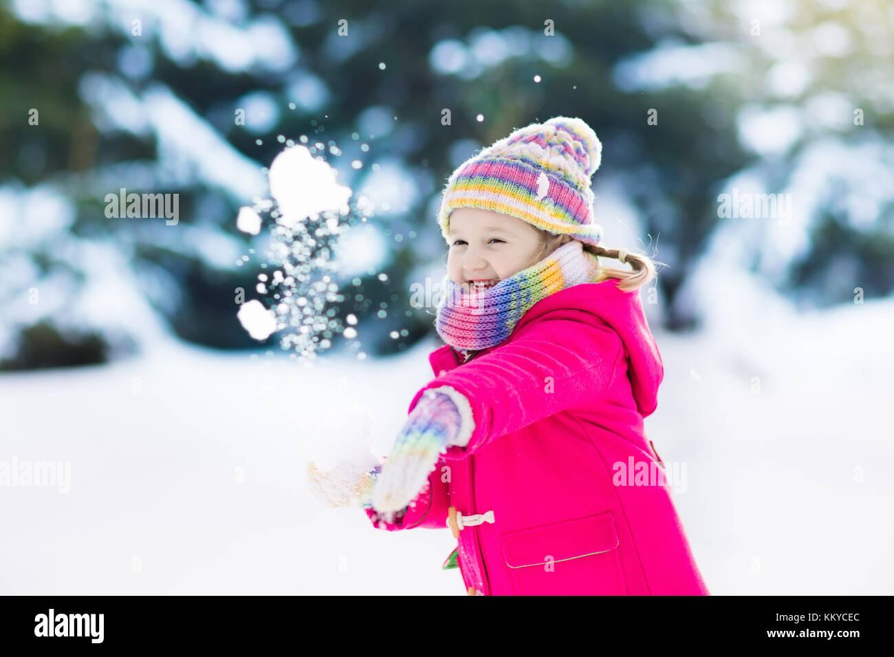 Child playing with snow in winter. Little girl in colorful jacket and ...