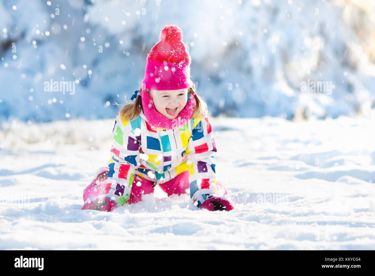 Child playing with snow in winter. Little girl in colorful jacket and ...