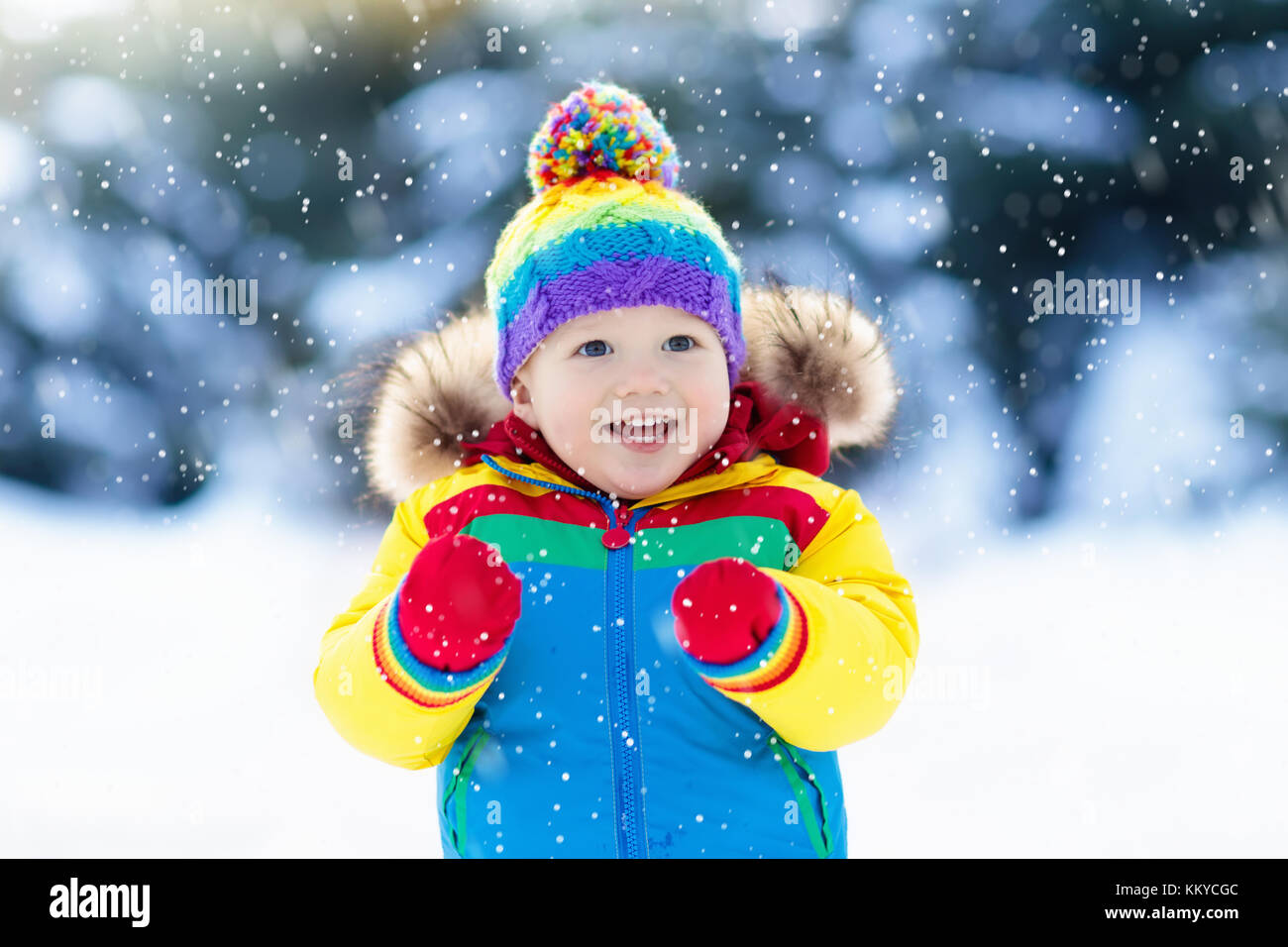 Child playing with snow in winter. Little boy in colorful jacket and ...