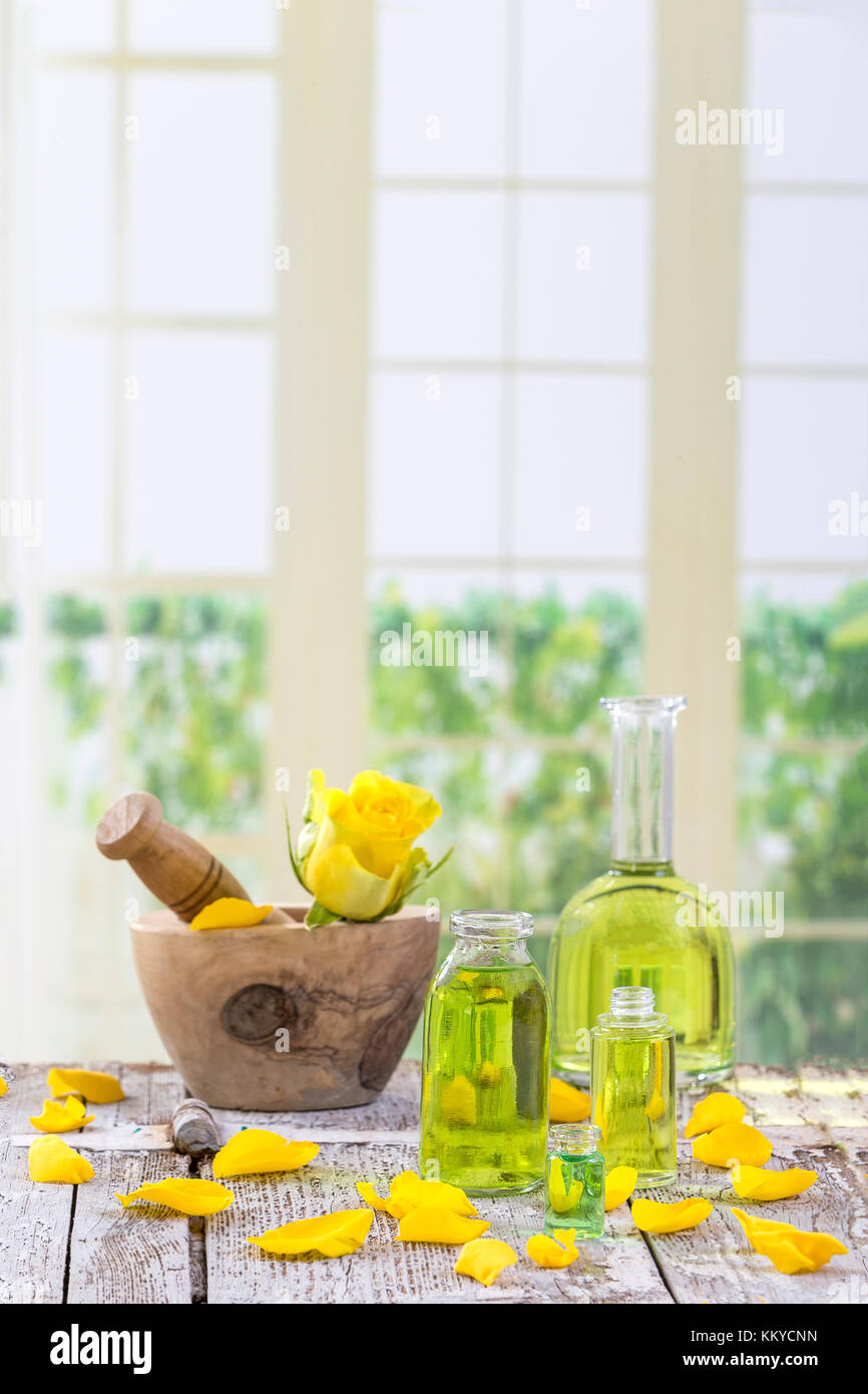 Yellow roses flowers on a wooden mortar for herbal medicine on windows background Stock Photo