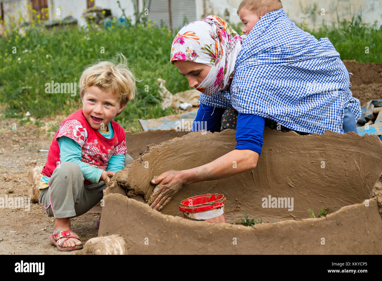 Kurdish woman carrying her baby on her back and works to make tandoor oven, in Diyarbakir, Turkey. Stock Photo