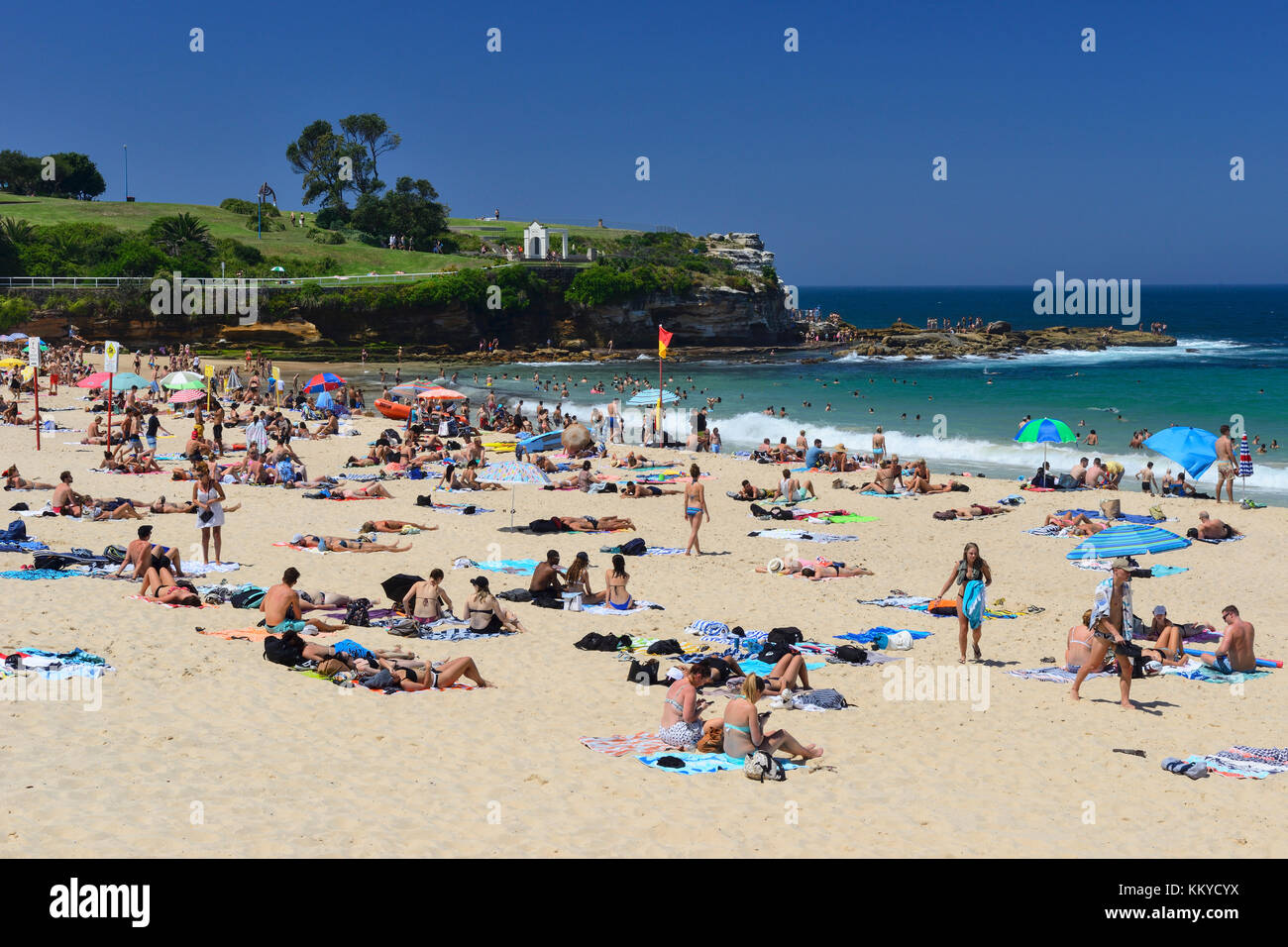Sunbathers on Coogee Beach, with Dunningham Park on headland in background, Coogee, Sydney, New South Wales, Australia Stock Photo