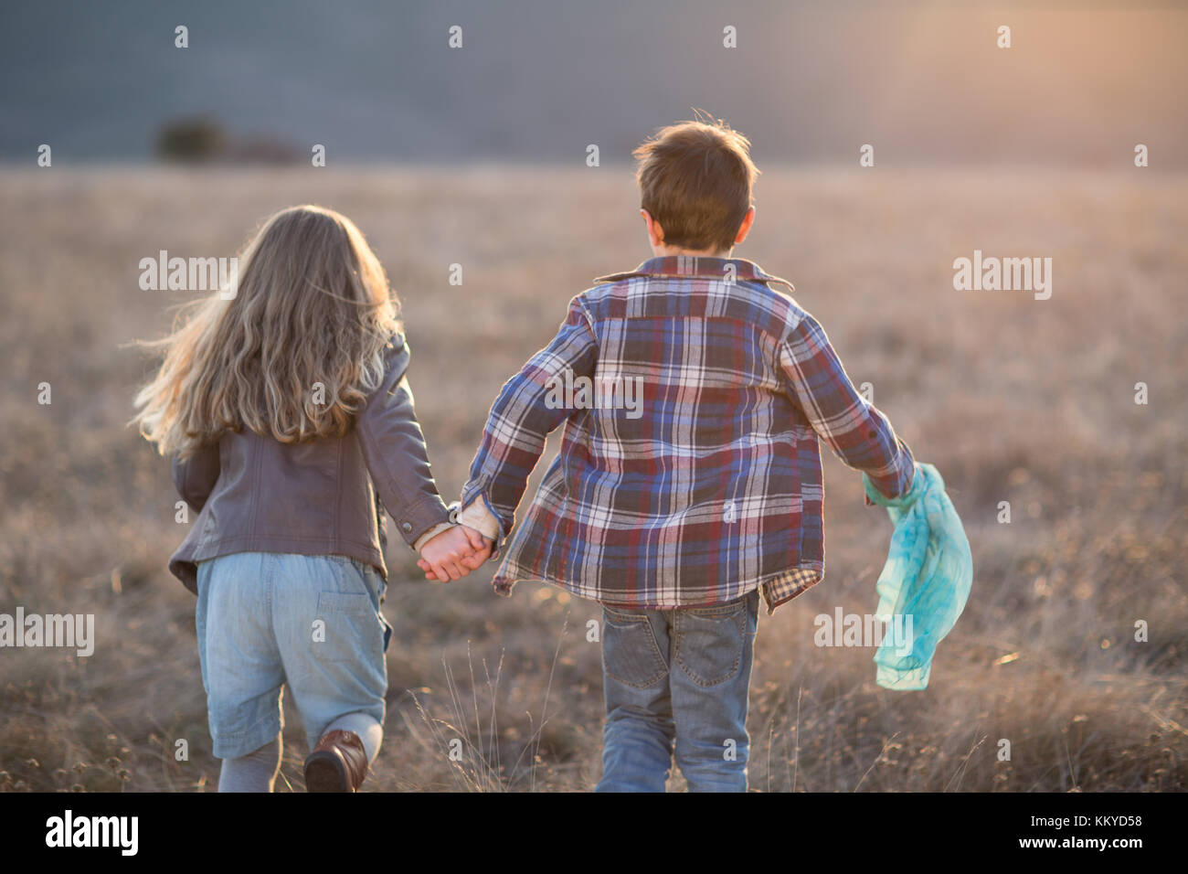 Kids Boy And A Girl Running On Sunny A Field Holding Hands Stock Photo Alamy