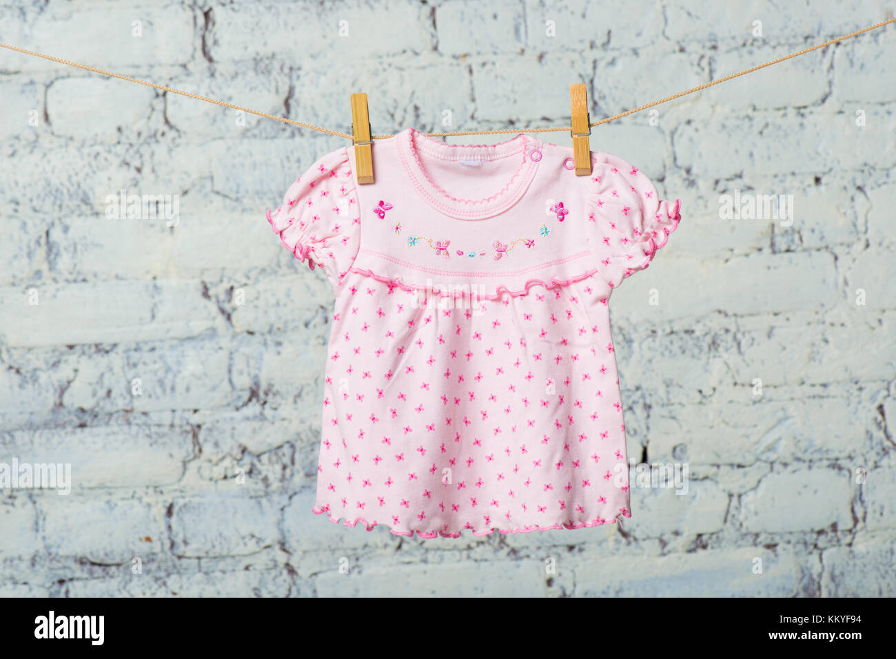A baby dress dries on a rope against a white brick wall Stock Photo - Alamy