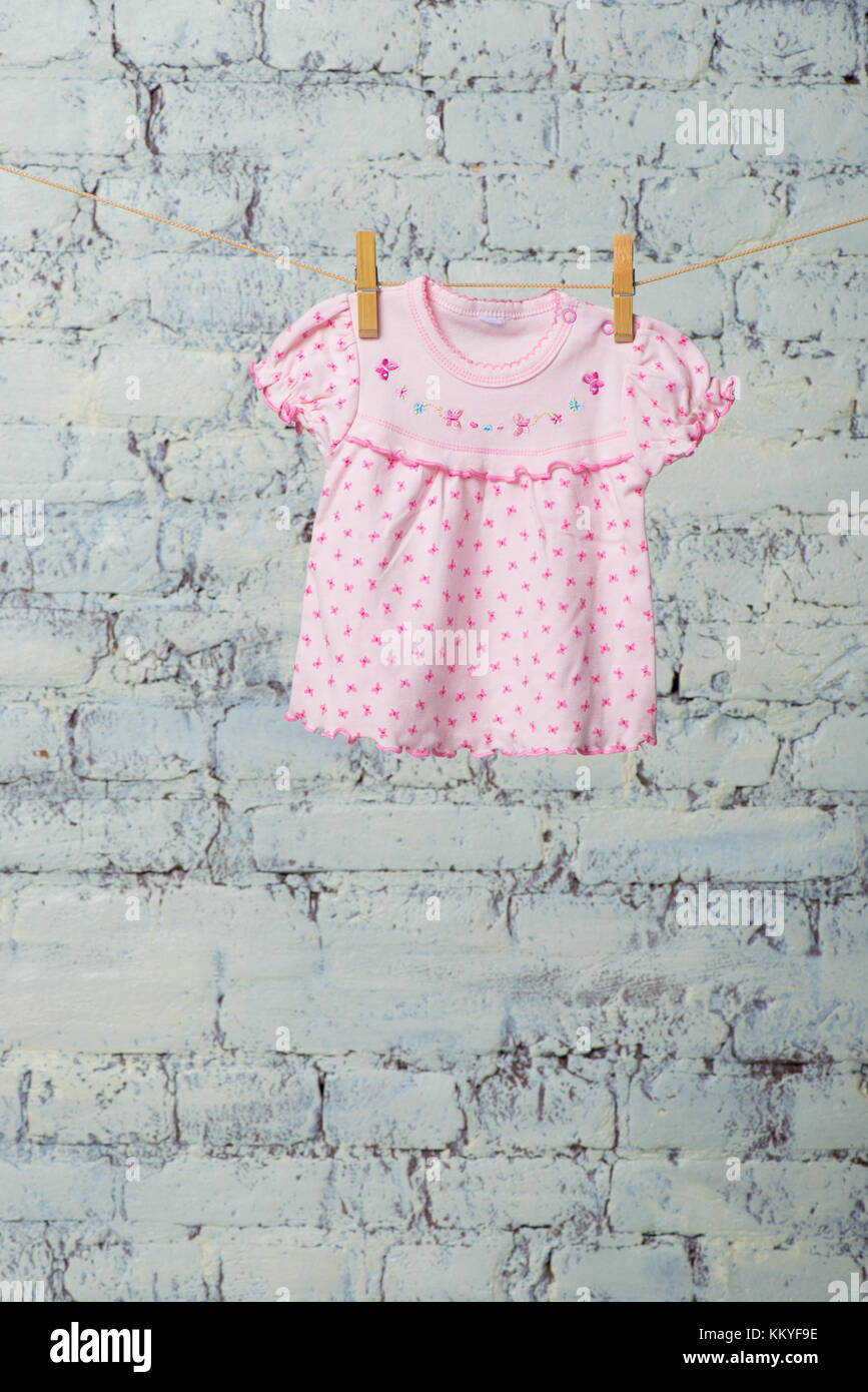 A baby dress dries on a rope against a white brick wall Stock Photo - Alamy