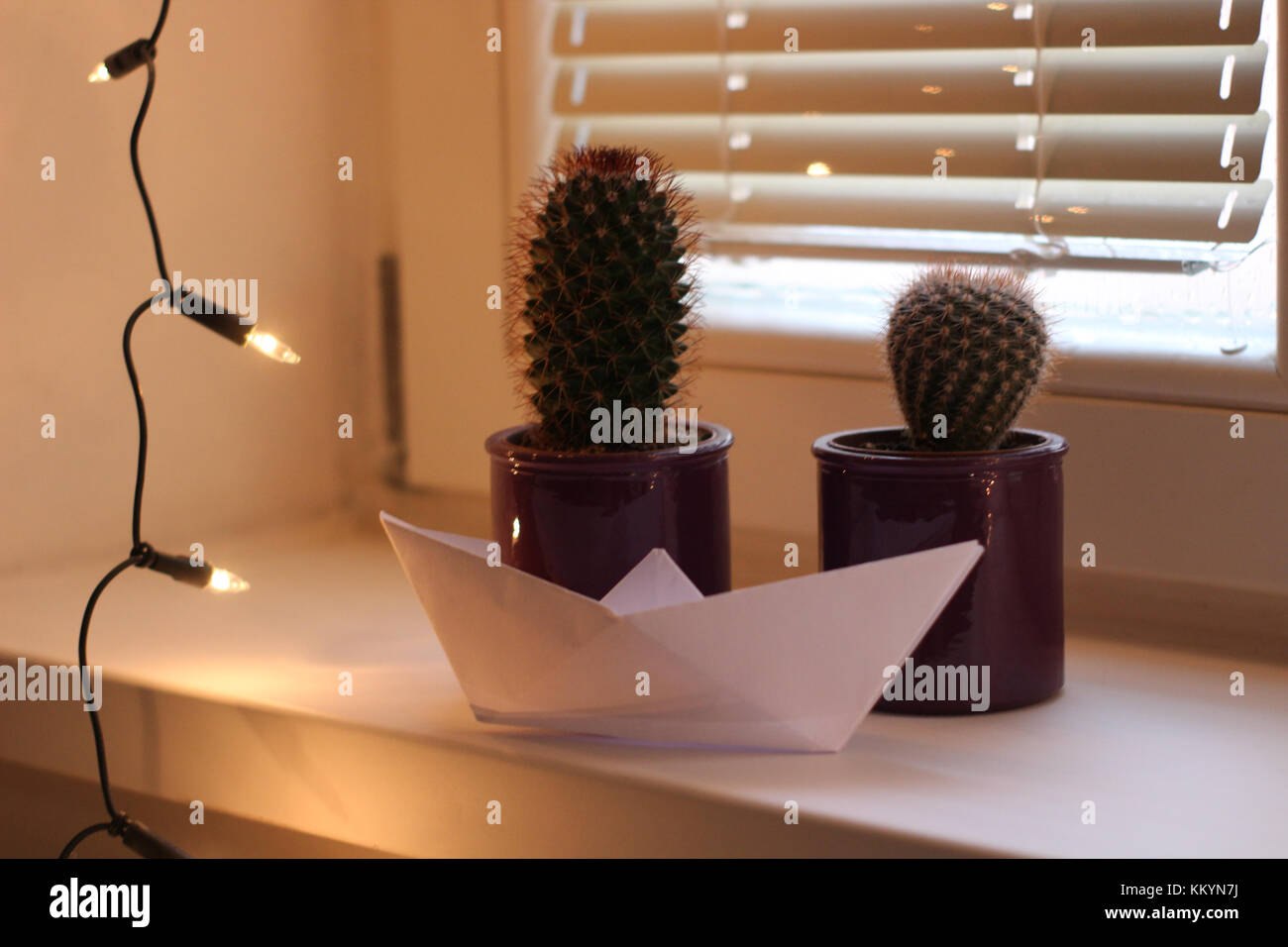 christmas lights cactus and a paper boat on a home window decoration Stock Photo