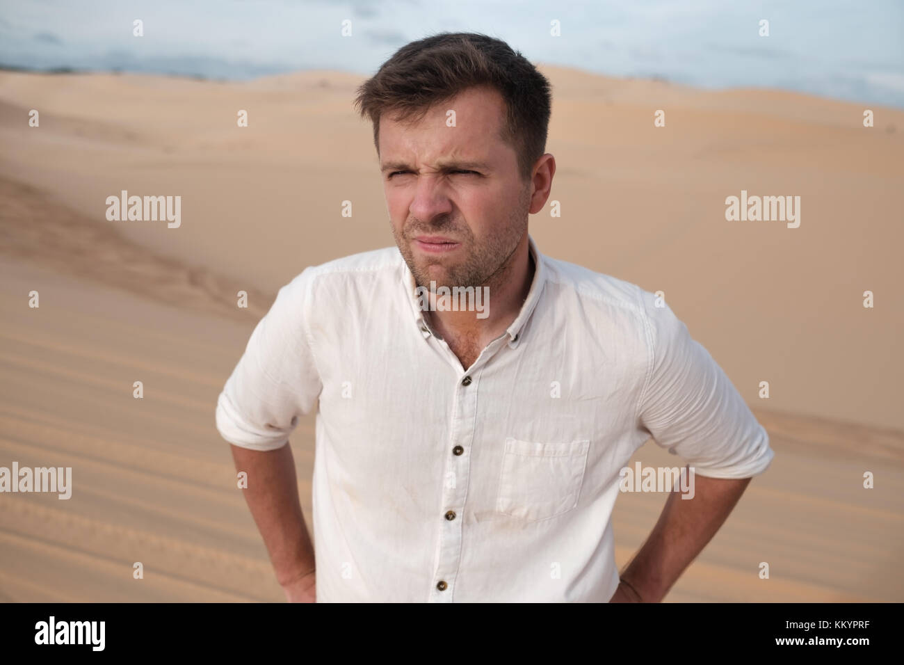 angry man with grimace on his face in desert alone. He is lost and is tired to do something Stock Photo