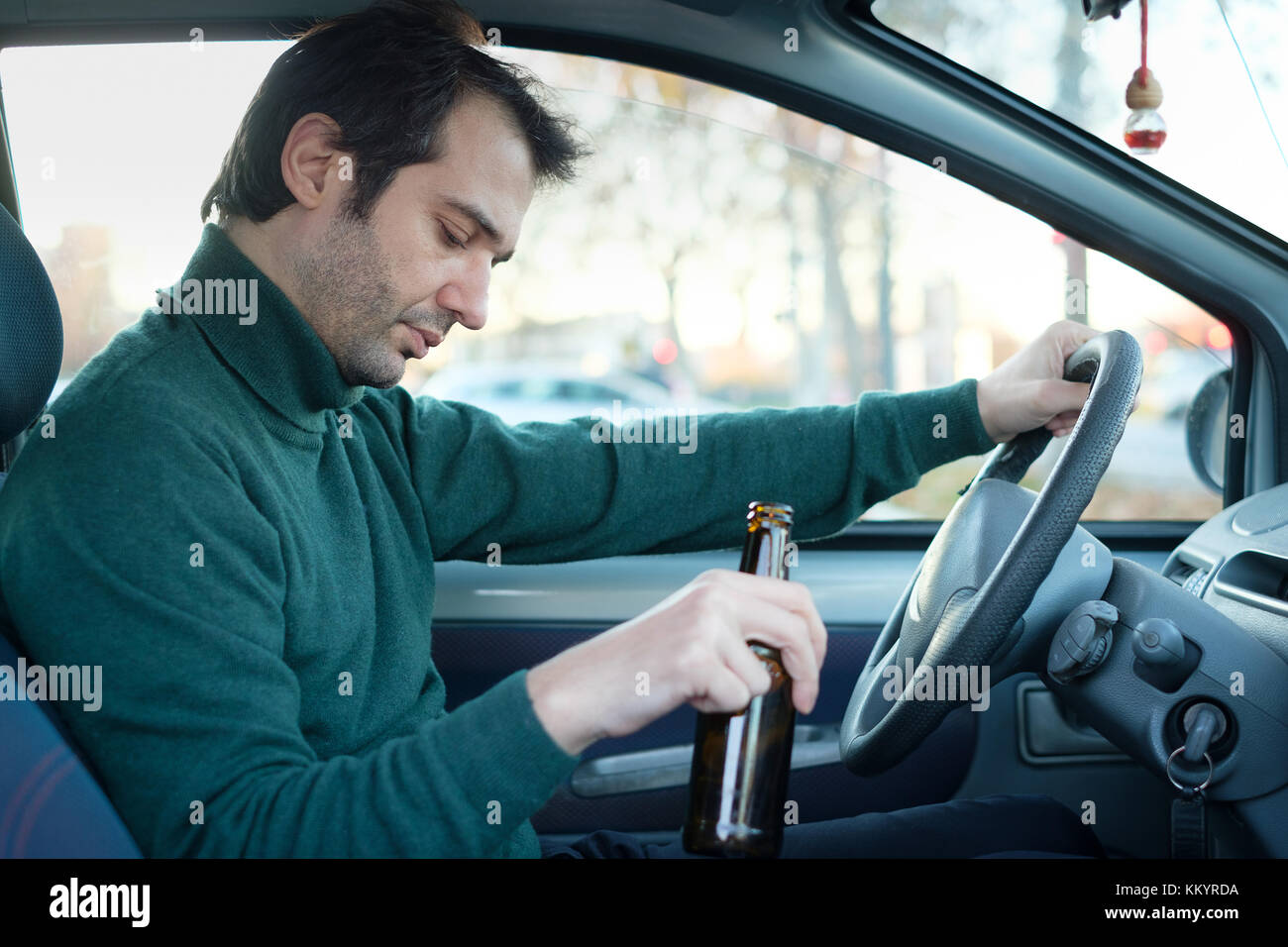 Don't drink and drive campaign.Drunk and driving a car with a bottle of alcohol Stock Photo