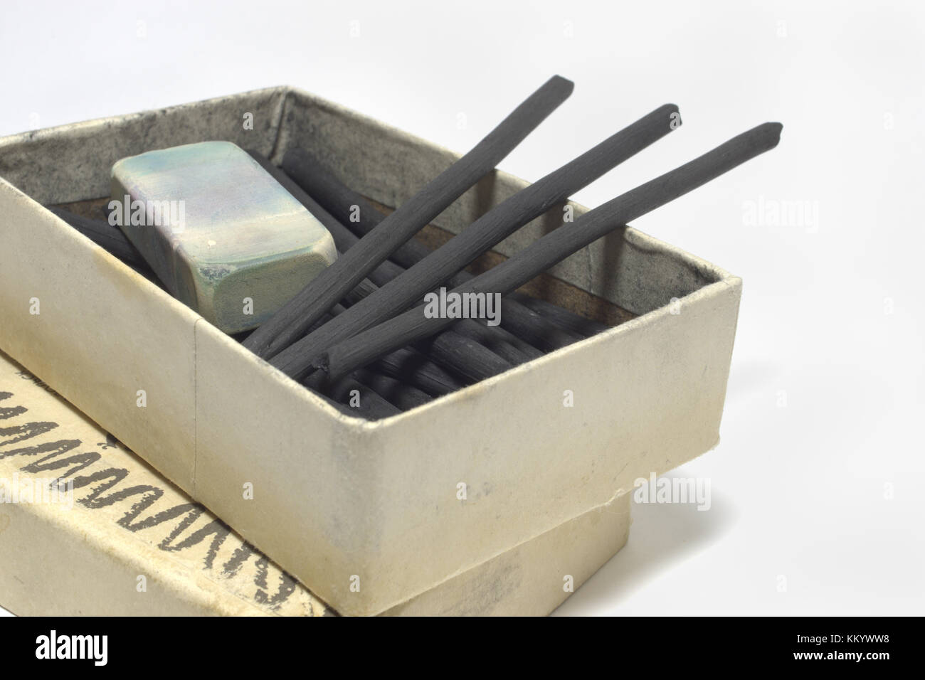 cardboard box with natural charcoal sticks and dirty eraser. vintage art materials for draw. Closeup Stock Photo