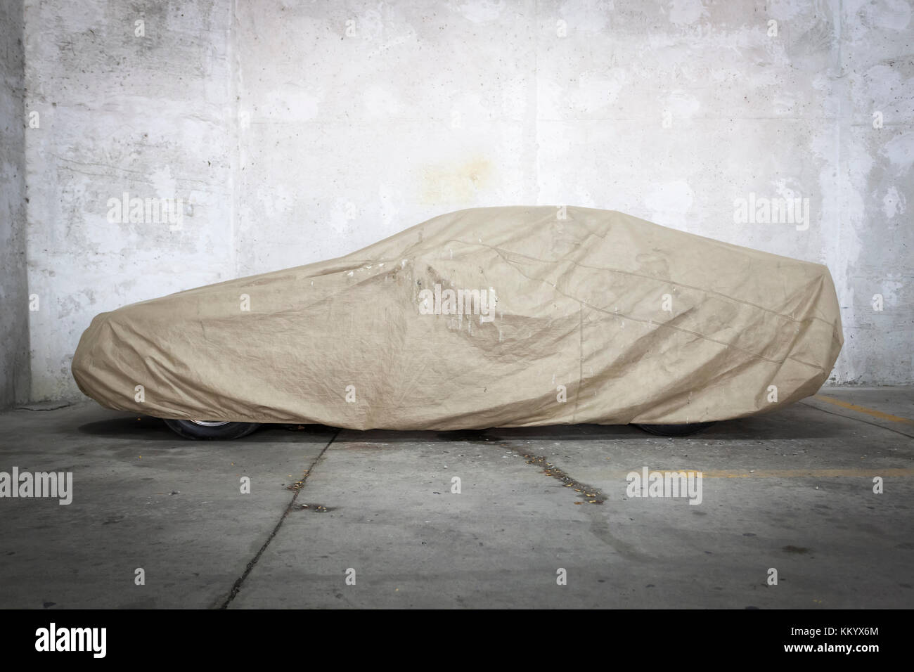 Car under a protective cover parked in parking garage Stock Photo
