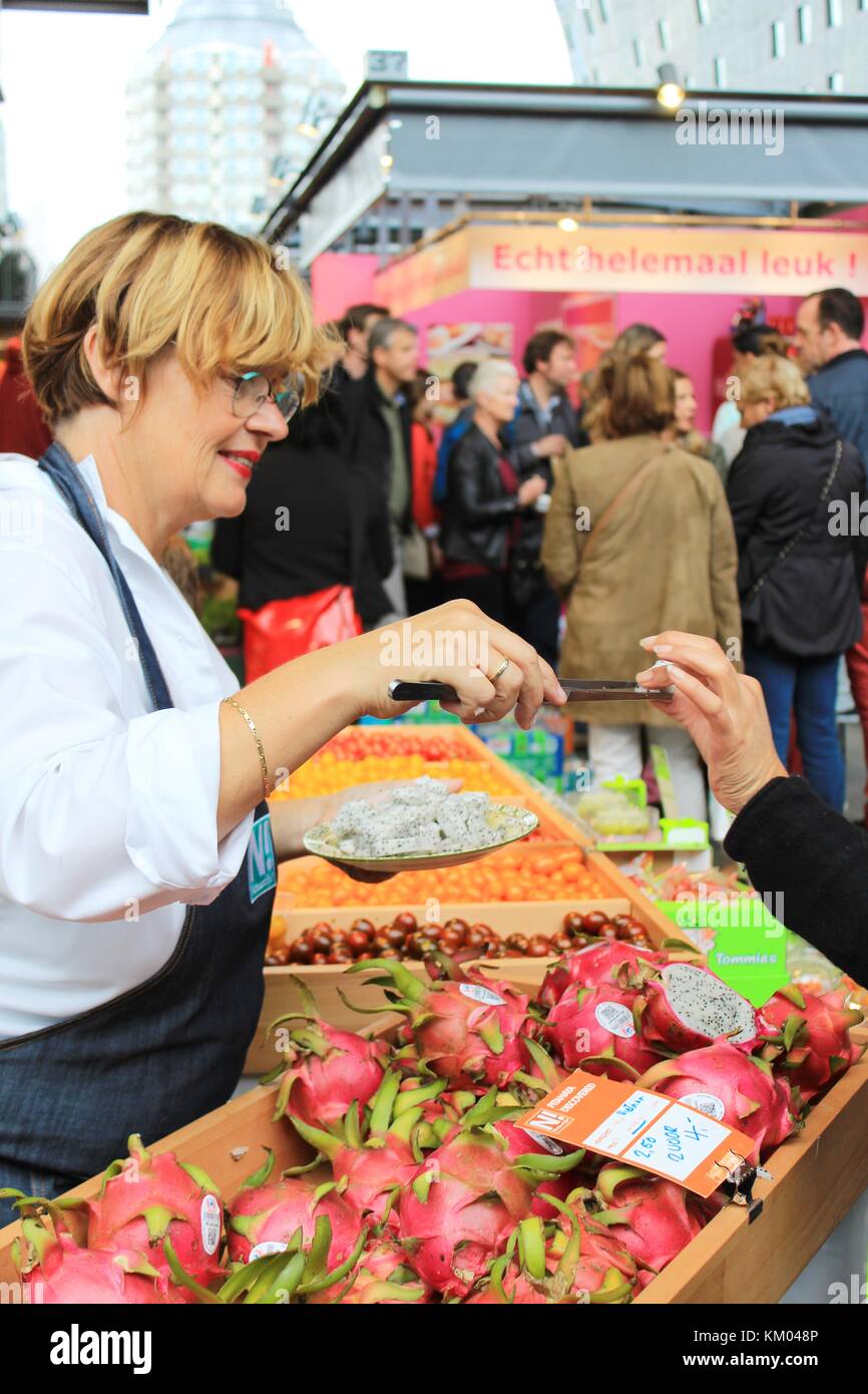 The seller gives an exotic fruit sample to a buyer at the fresh market