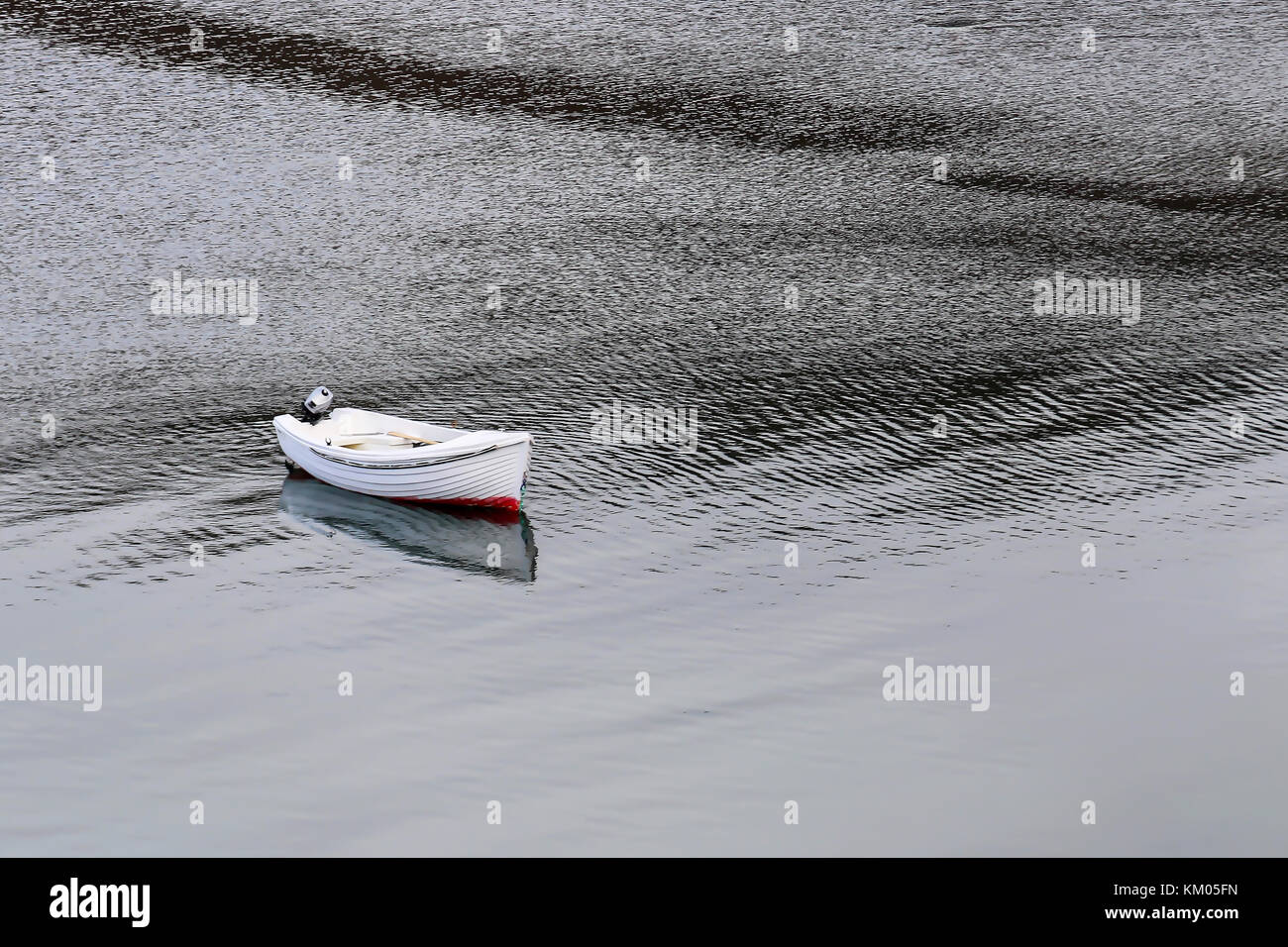 Single white rowboat sits on ocean surface Stock Photo