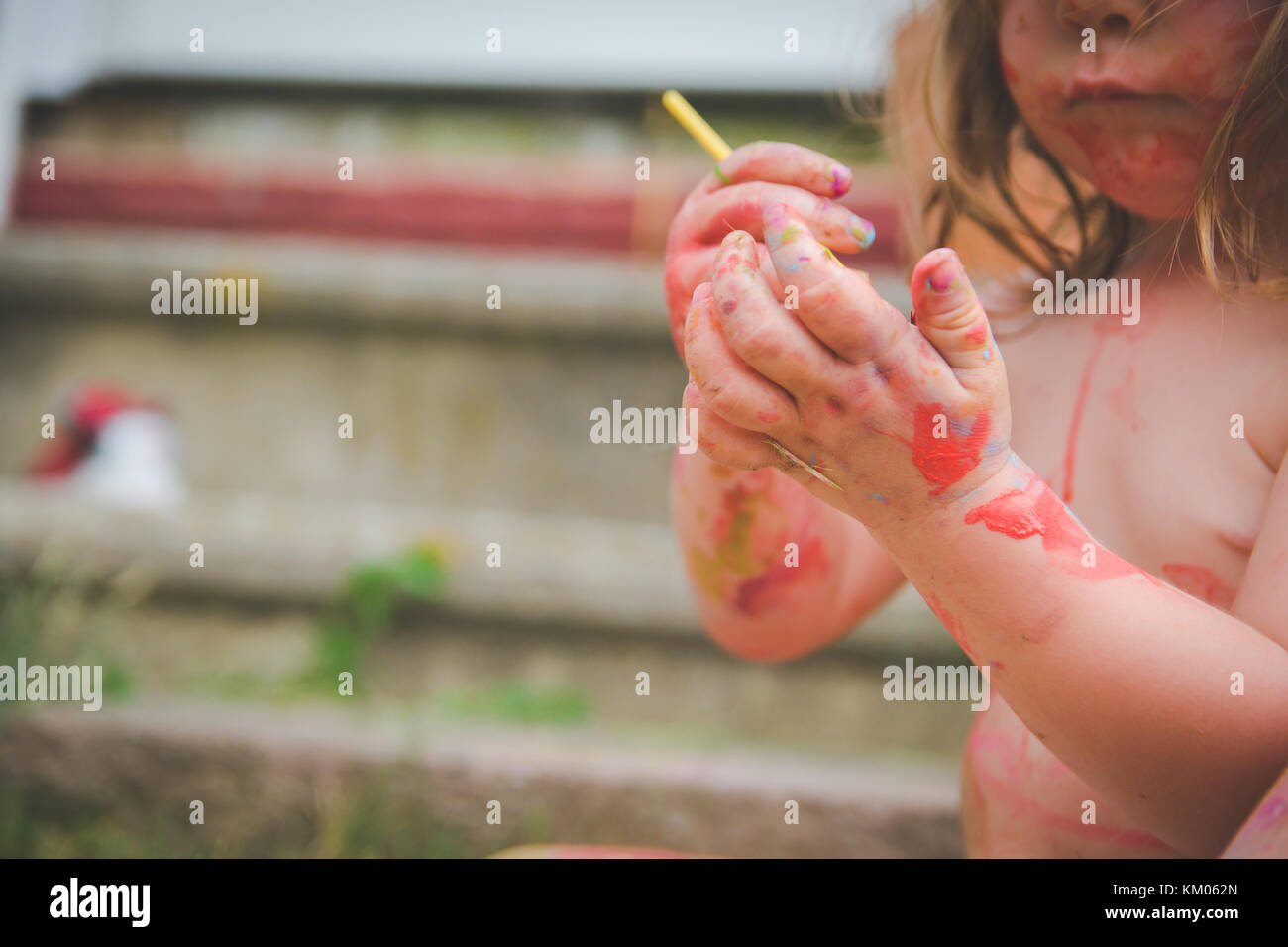 A toddler paints on her hands. Stock Photo